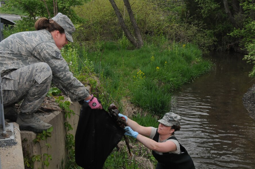 Master Sgt. Andrea Stine, 211th Engineering Installation Squadron, personnel,  hands garbage she collect from the stream in Area 1 at Fort Indiantown Gap, Annville, Pa., to Staff Sgt. Ashley Kessler, 148th Air Support Operations Squadron, personnel.  These two Airmen were part of a group of nine that volunteered to participate in an Earth Day clean-up, April 22. (U.S. Air Force photo by Airman 1st Class Claire Behney)