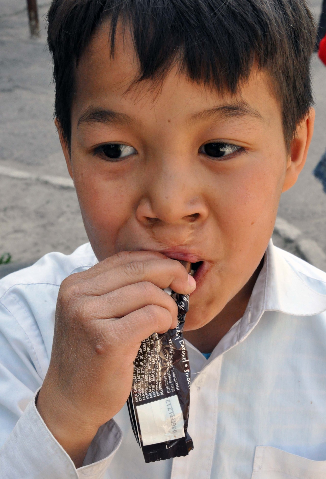 A Kyrgyz boy from the Sokulukskaya Special Boarding School/orphanage enjoys a candy bar from Airmen at the Transit Center at Manas, Kyrgyzstan, April 23, 2010. He, like many of the 270 children there, had cleft palette surgery. Airmen donated flour, oil, rice, and pasta to the school. (U.S. Air Force photo/Staff Sgt. Carolyn Viss)