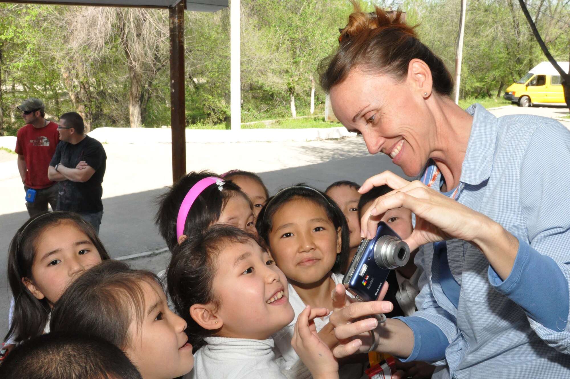 Master Sgt. Mary Conner, an Airman from the Transit Center at Manas, Kyrgyzstan, shows children from the Sokulukskaya Special Boarding School/orphanage photos she just took of them April 23, 2010. Airmen donated flour, oil, rice, and pasta for the 270 children there, who have had or need cleft palette surgery. (U.S. Air Force photo/Staff Sgt. Carolyn Viss)