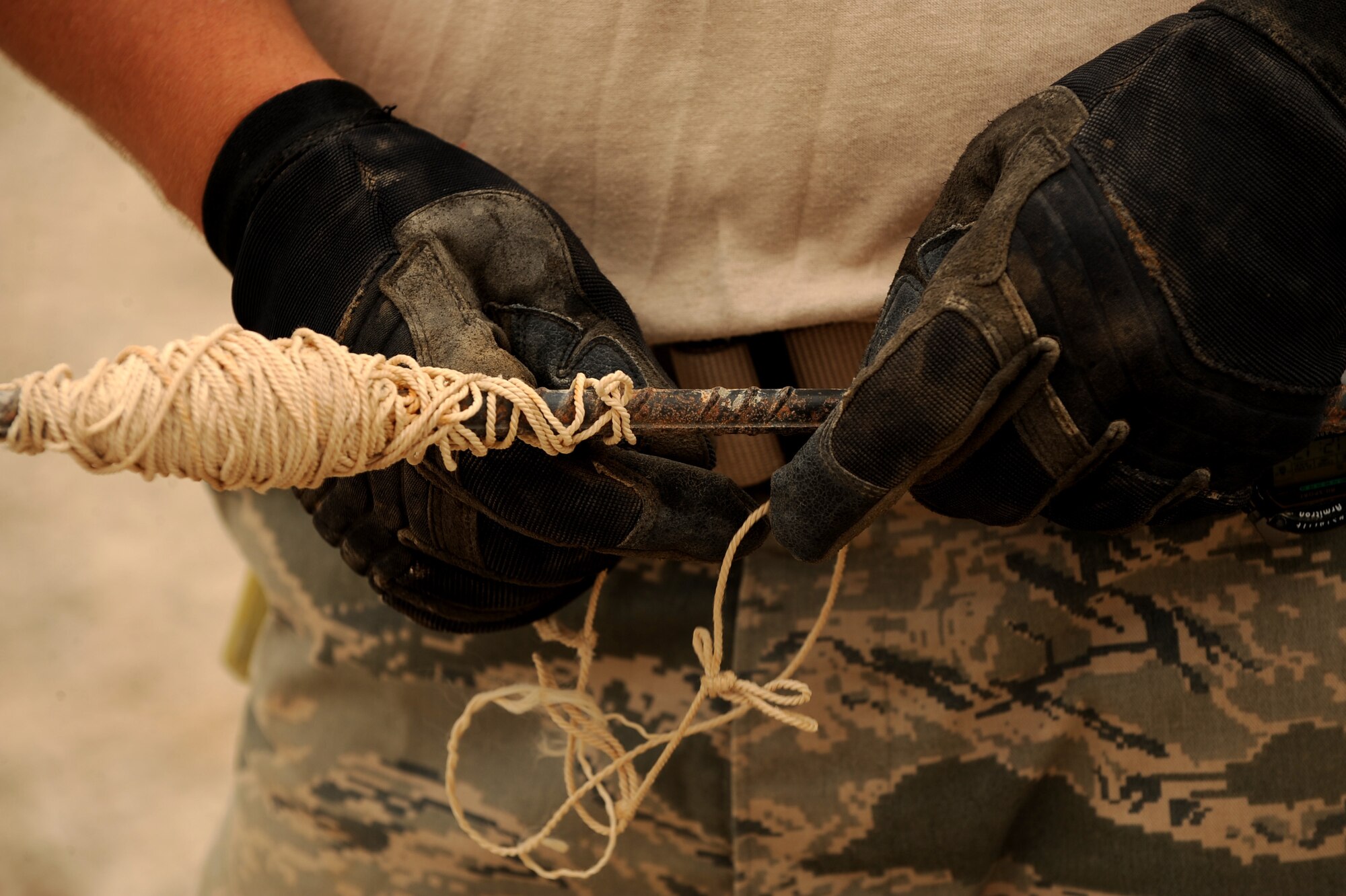 Senior Airman Adam Bishop, a heavy equipment operator assigned to the 1st Expeditionary RED HORSE Group, rolls up rope used between stakes at an evaporation pond work site, April 19, 2010, at Camp Leatherneck, Afghanistan. While a regular RED HORSE squadron has between 70 to 130 Airmen; the team of Total Force Airmen at Camp Leatherneck has had to adjust with limited recourses and personnel.  Normal decisions that may take a month can take two days. (U.S. Air Force photo/Staff Sgt. Manuel J. Martinez/released)