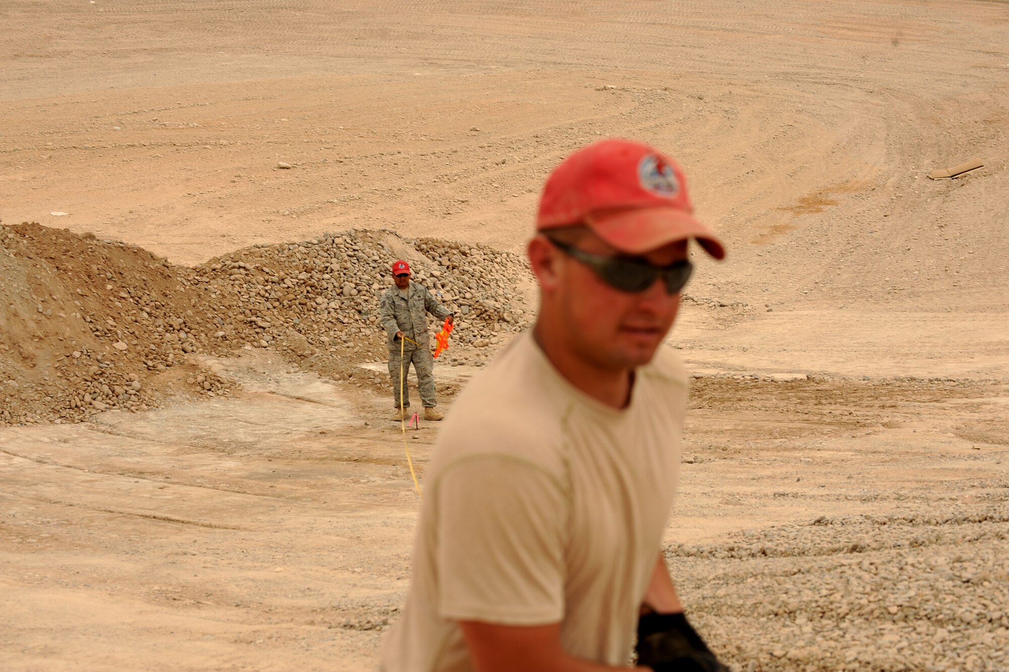 Senior Airman Adam Bishop, front, a heavy equipment operator, and Tech. Sgt. Alfredo Perez, a project manager, both assigned to the 1st Expeditionary RED HORSE Group, measure the distance between stakes at an evaporation pond work site, April 19, 2010, at Camp Leatherneck, Afghanistan. Although the team has been in country less than a month, the team is working on six projects worth about $2 million. The projects include the new RED HORSE compound, a K-SPAN metal tent for the U.S. Army's inbound 502nd Bridge Maintenance Brigade, building a  foundation for a new fire station, grading a burn pit, constructing an evaporation pond to collect waste water and a river-bed extension to prevent flooding, all to be completed by mid July. (U.S. Air Force photo/Staff Sgt. Manuel J. Martinez/released)