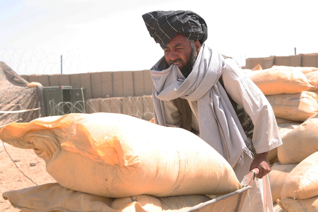 A Marjah farmer wheels out bags of fertilizer and crop seeds at the Civil-Military Operations Center at Camp Hansen, Marjah, Afghanistan, April 25.  The food zone program, led by the Helmand Provincial Reconstruction Team, has distributed more than 1,066 packages of fertilizer and seeds to farmers throughout northern Marjah. This program, along with other programs led by the Helmand Provincial Reconstruction Team, assists farmers cope with a harsh harvest season, as well as providing an alternative to harvesting poppy, a major source of cash flow for Taliban forces.
