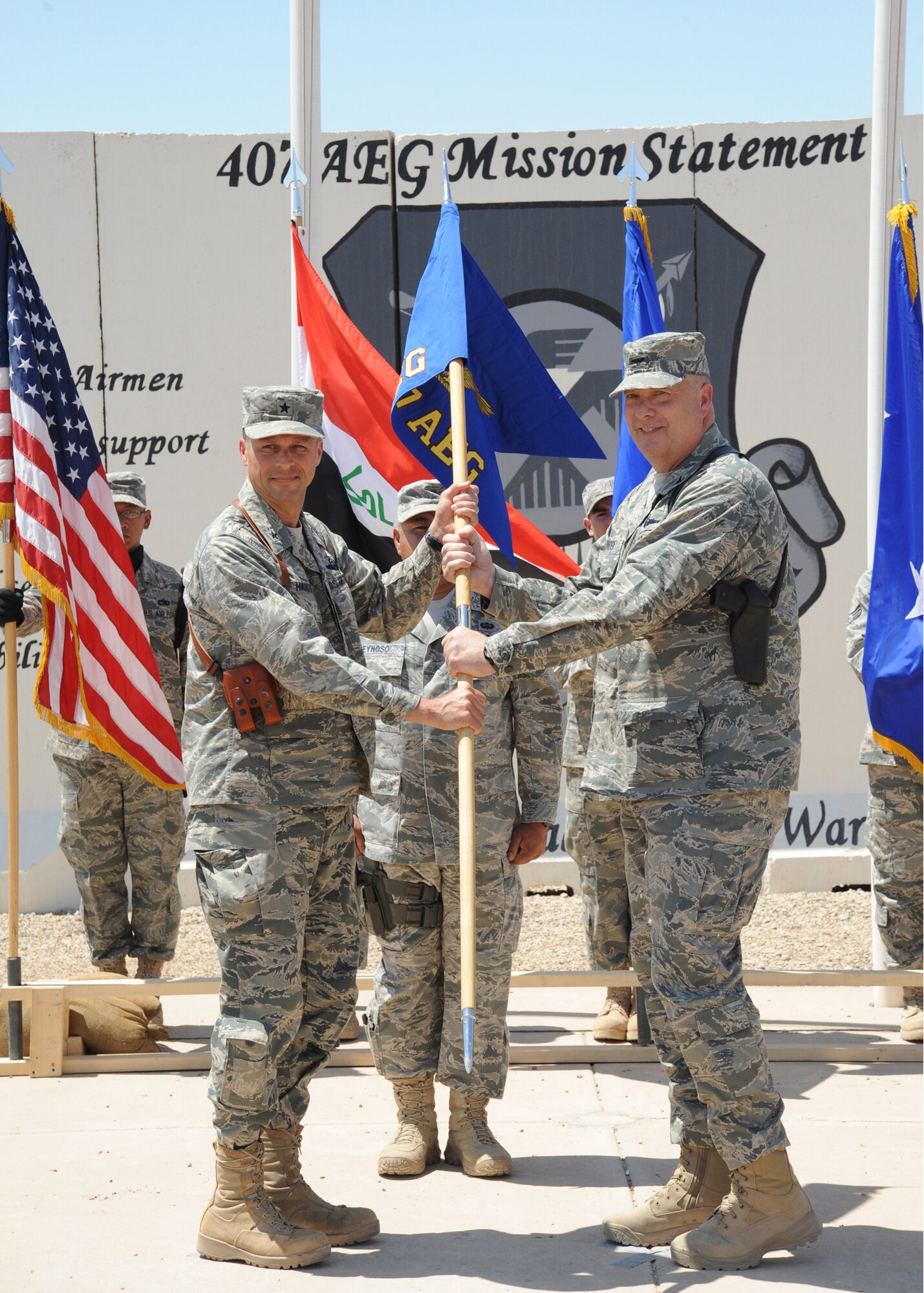 Air Force Brig. Gen. Scott Hanson (left), commander of the 321st Air Expeditionary Wing, hands the guidon to Col. James Linder, incoming commander of the 407th Air Expeditionary Group during a change of command ceremony Ali Air Base, Iraq, April 24, 2010. The mission of the 321st AEW is to train and advise the Iraqi air force in order to advance the foundational airpower capabilities of Iraqi Airmen. (U.S. Air Force photo/Master Sgt. Trish Bunting/Released)