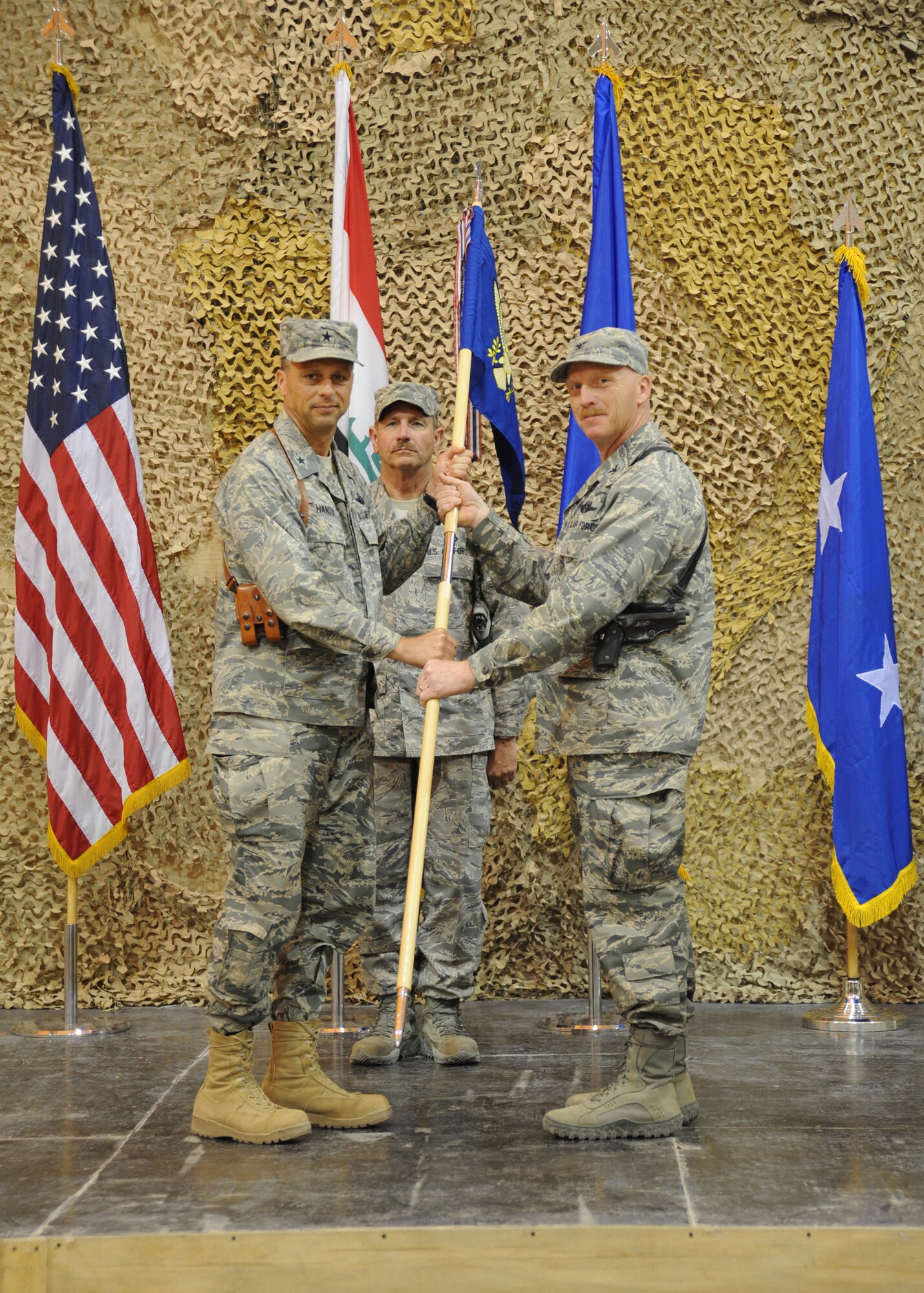 Air Force Brig. Gen. Scott Hanson (left), commander of the 321st Air Expeditionary Wing, hands the guidon to Col. James Linder, incoming commander of the 407th Air Expeditionary Group during a change of command ceremony Ali Air Base, Iraq, April 24, 2010. The mission of the 321st AEW is to train and advise the Iraqi air force in order to advance the foundational airpower capabilities of Iraqi Airmen. (U.S. Air Force photo/Master Sgt. Trish Bunting/Released)