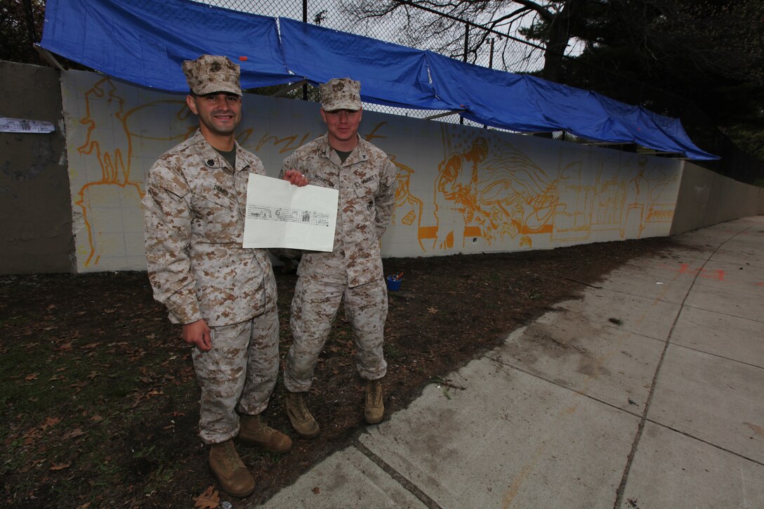 Staff Sgt. Jorge Dimmer, graphics chief, Marine Corps Recruiting Command, and Lance Cpl. Pablo Morrison, combat graphic reproduction specialist, Marine Corps Base Quantico, Va., show off the design of the mural in Hyde Park commemorating Marine Week Boston April 27, 2010. Dimmer is slated to become a warrant officer Feb. 1, 2011 after 12 years of enlisted service.