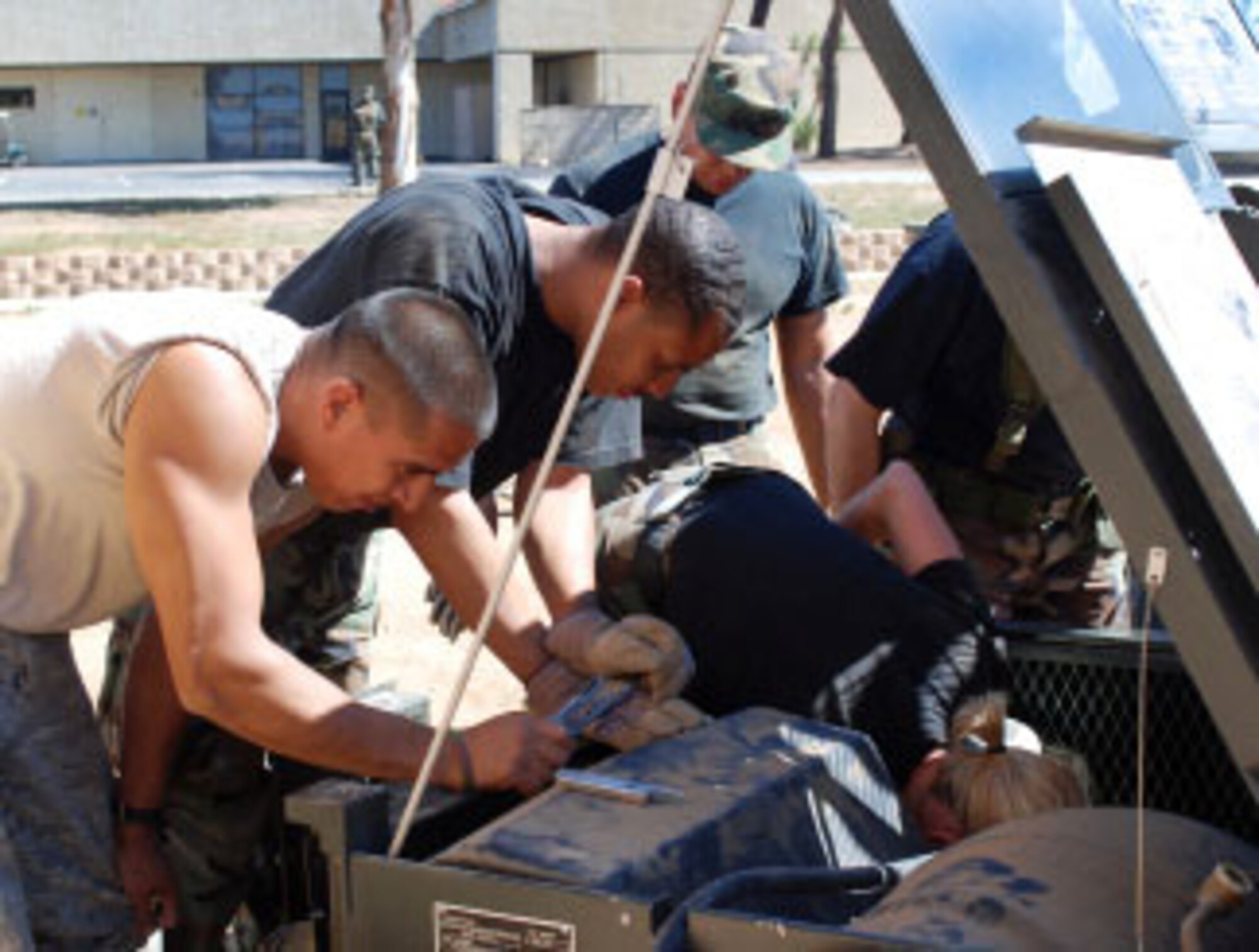 Senior Airman Steven Hernandez (left) and Staff Sgt. Eric Sherman, both of the 452nd Civil Engineering Squadron, offer assistance to a member of the 163rd Civil Engineering Squadron who works on an element at the bottom of a field deployable environmental control unit, April 8. (U.S. Air Force photo by Megan Just)
