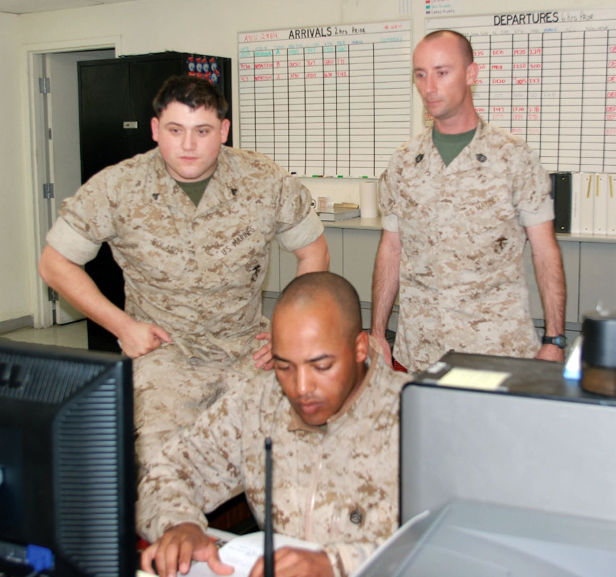 Cpl. Bryan Boland (left), Gunnery Sgt. Jeremiah Rick (back) and a visiting Marine check the single mobility system computer in the A/DACG office inside the deployment hangar. (U.S. Air Force photo by Megan Just)