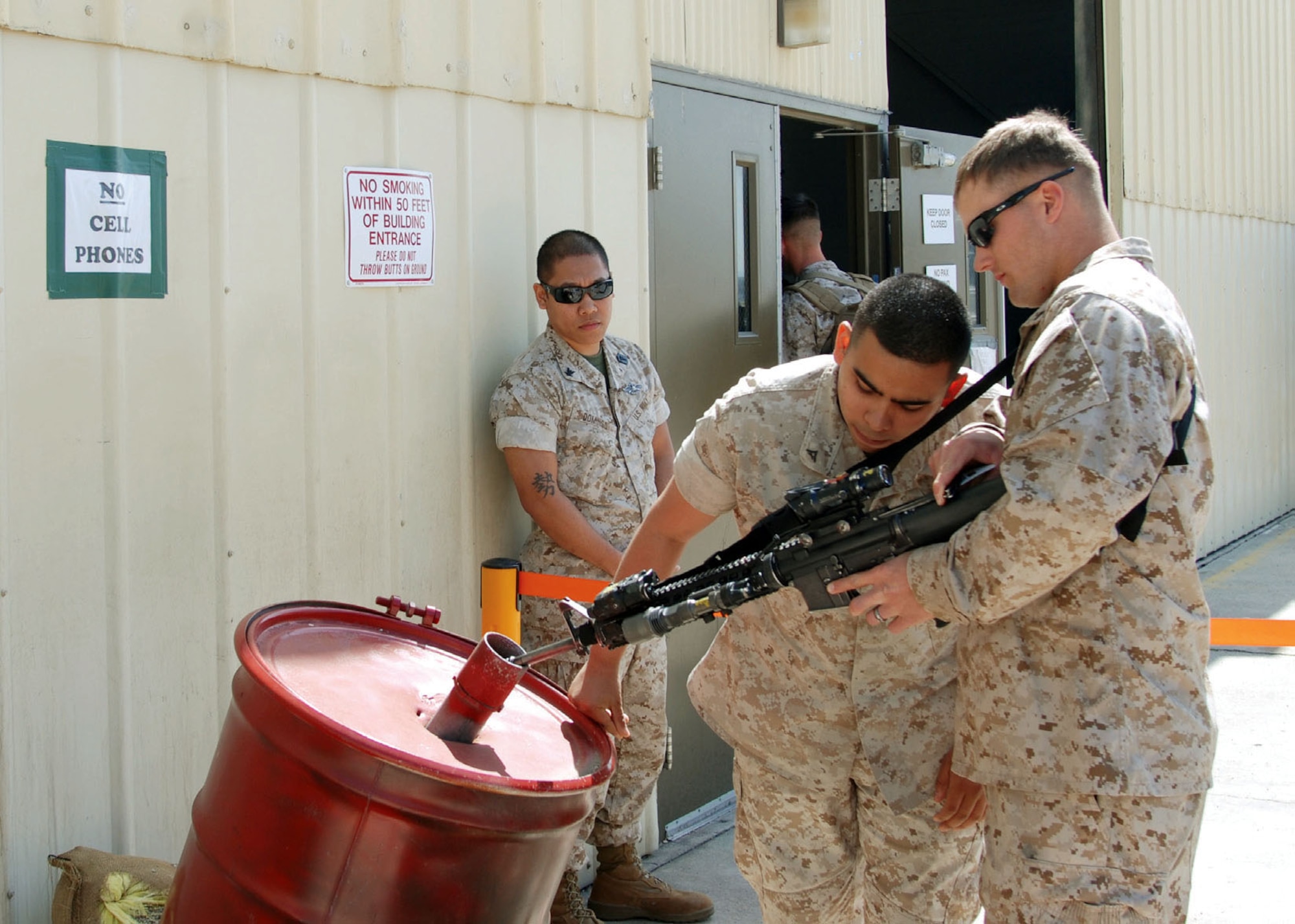 A/DACG Marine Corps Lance Cpl Julian Gonzalez checks the barrel of a Marine’s M-16/A4 March 26 while Navy Petty Officer 2nd Class Jonathan Domingo, also with the A/DACG, looks on. Corporal Gonzalez visually inspects the barrel of every weapon carried into the deployment hangar at March ARB. (U.S. Air Force photo by Megan Just)