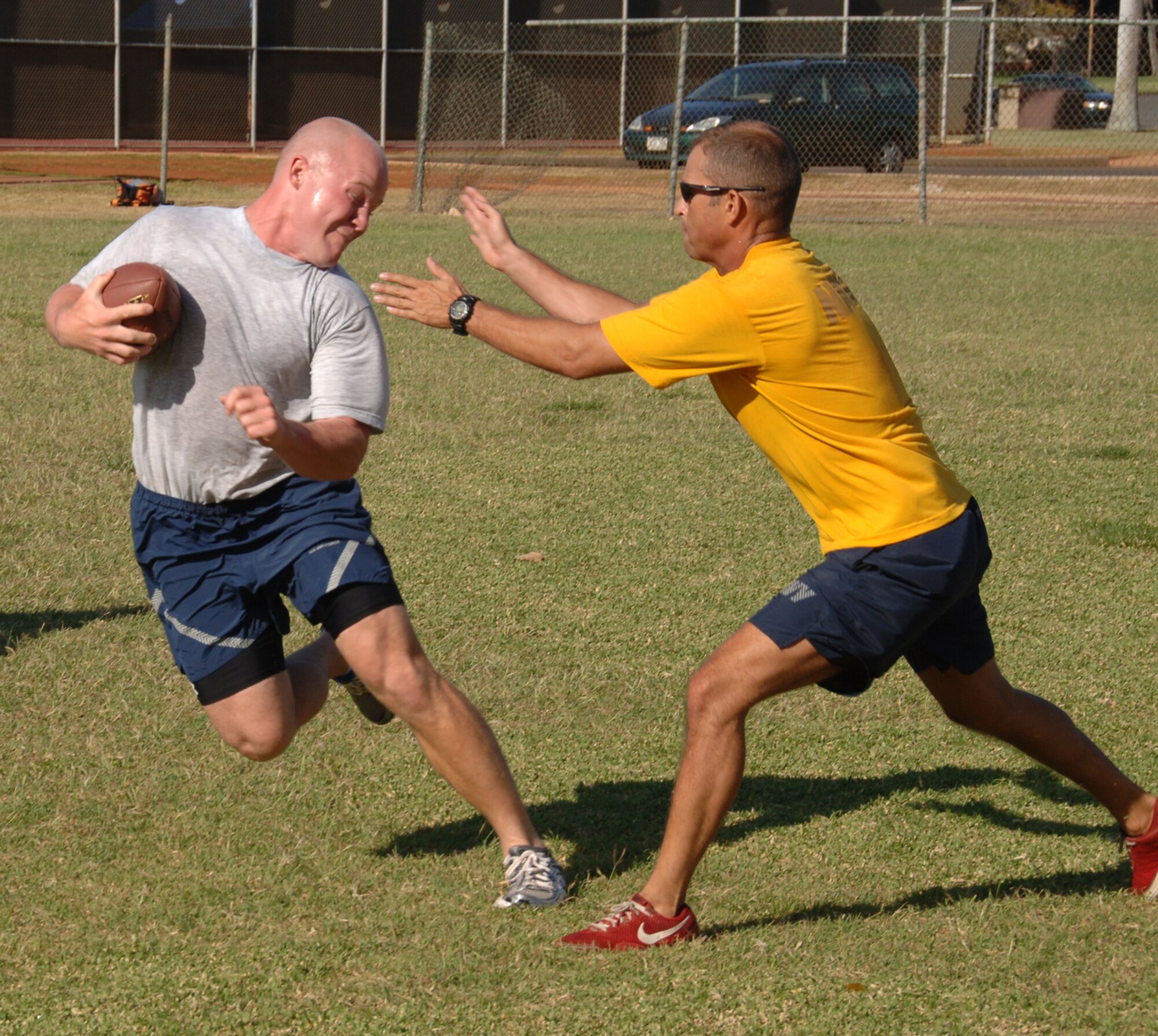 Petty Officer 1st Class Kenneth Maust tags Staff Sgt. David Fritz, 65 Airlift Squadron/Executive Transport Detachment, during a game of football behind the gym April 16 at Joint Base Pearl Harbor Hickam, Hi. The 65 AS, an Air Force unit, and the ETD, a Navy unit, are sister squadrons who work together to support the joint base mission. (U.S. Air Force photo by Senior Airman Nathan Allen)