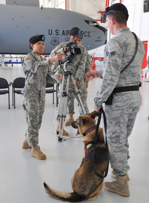 Army Private 1st Class Lisa Valzco, combat documentation production specialist, interviews Senior Airman Benjamin Lee, 316th Security Force Squadron military working dog handler, as Private 1st Class Rakeem Johnson, combat documentation production specialist, center, rolls video after a MWD demonstration at the 459th Air Refueling Wing Hangar on Joint Base Andrews, Md., 10 April 22, 2010.  The video team are Defense Information School students working on a final product to be graded prior to graduating May 4.