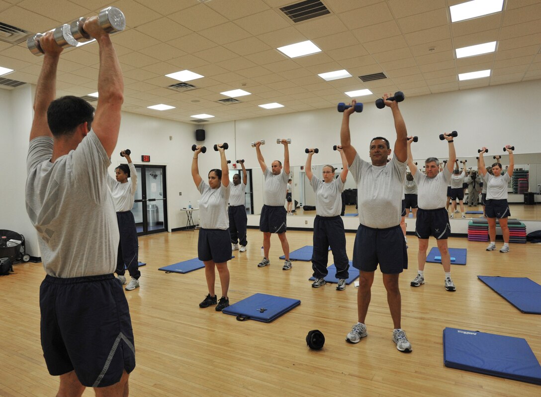 Master Sgt. Shaun Withers, left, Air National Guard Readiness Center multimedia photographer, leads ANGRC members through a muscle strengthening exercise with dumbbells in the aerobics room at the West Fitness Center at Joint Base Andrews, Md., April 22, 2010.  The members are in week eight of a 12-week fitness program to educate unit members on the proper way to exercise as well as nutritional eating habits.  