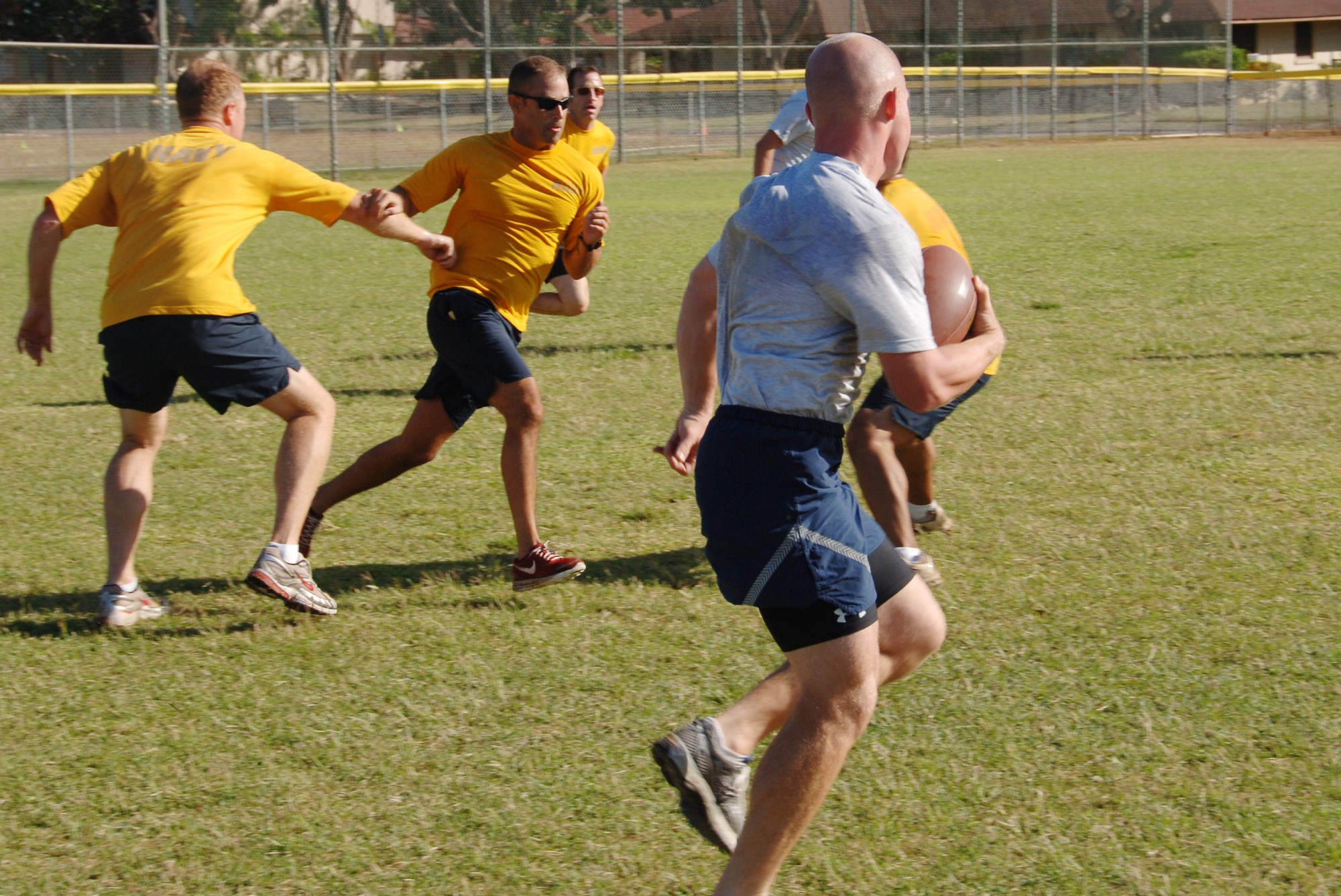 Staff Sgt. David Fritz, 65 Airlift Squadron/Executive Transport Detachment, follows his blockers as he returns a kickoff during a game of football behind the gym April 16 at Joint Base Pearl Harbor Hickam, Hi. The 65 AS, an Air Force unit, and the ETD, a Navy unit, are sister squadrons who work together to support the joint base mission. (U.S. Air Force photo by Senior Airman Nathan Allen)