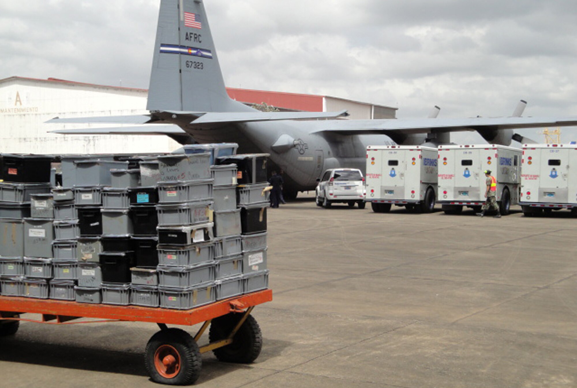 Several armored trucks full of seized gold, silver and jewels wait to be unloaded April 8 as security personnel protect a 302nd Airlift Wing C-130 at a Panamanian air base. The seized assets were part of a joint Panama-U.S. investigation into an international drug money laundering scheme in the Central American country. The Air Force Reserve's 302nd AW was tasked with flying the seized precious metals and jewels back to the United States for further processing by Department of Justice agencies. (Courtesy photo/Drug Enforcement Agency)