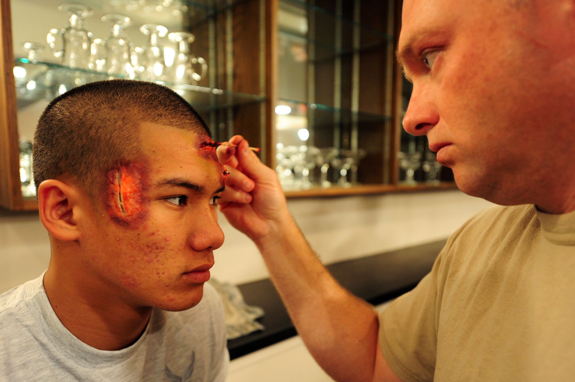 Tech. Sgt. Carl Struble, 19th Medical Group NCO-in-charge of physical therapy, adds moulage wounds to Airman 1st Class Frederick Burgos, 19th Force Support Squadron food services apprentice, April 21 prior to an exercise. Twelve Airmen, acting as victims, were part of an exercise for the unit compliance inspection at the war fit track. (U.S. Air Force photo by Senior Airman Steele C. G. Britton)