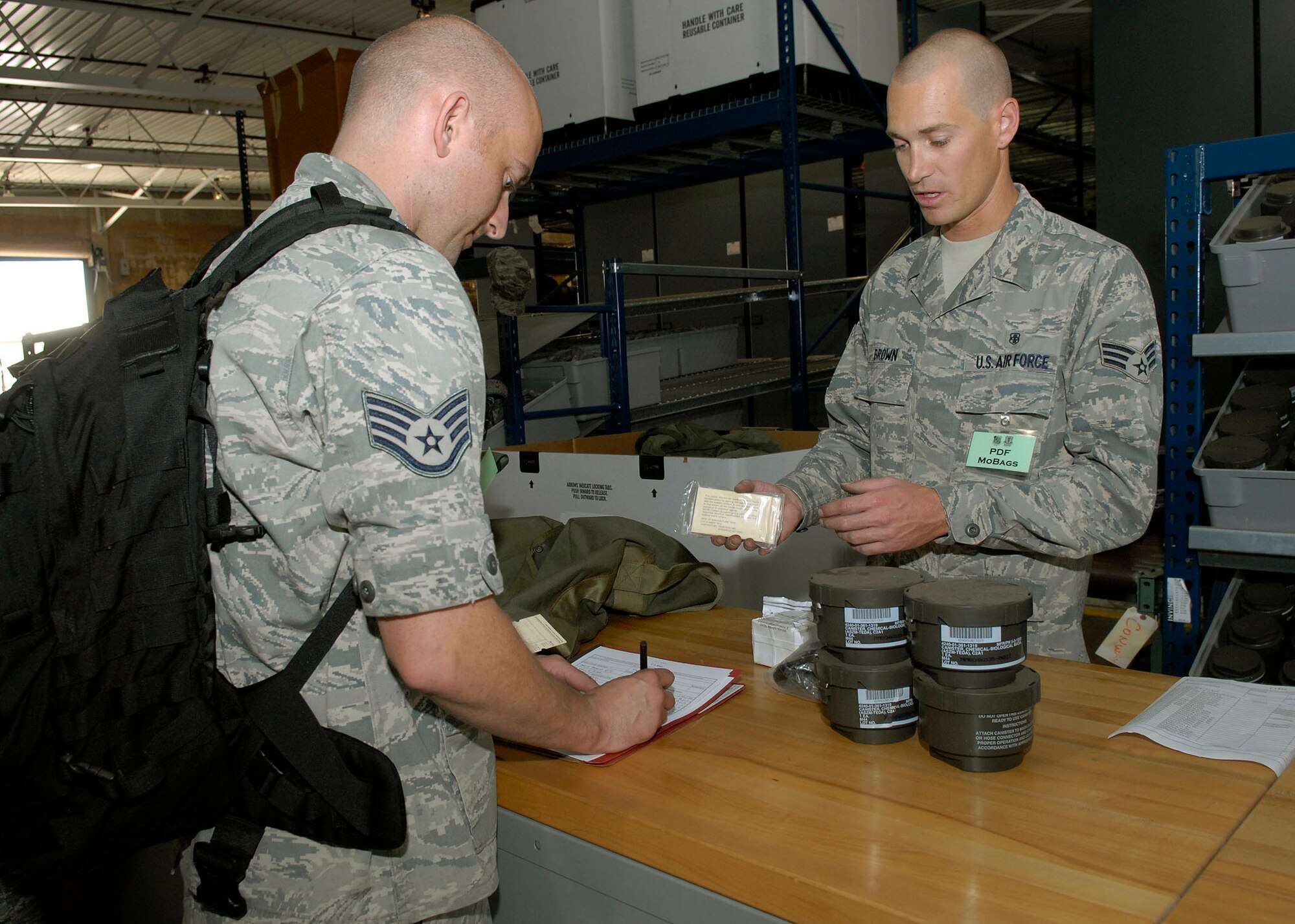 JOINT BASE PEARL HARBOR HICKAM, Hawaii--Senior Airman Matthew Brown, 15th Aerospace Medical Dental Squadron, verifies gas mask equipment serial numbers with Staff Sgt. Brent Davis, 15th Aircraft Maintenance Squadron, during an Operational Readiness Exercise at the Personnel Deployment Function building here  April 22. The PDF serves as the wing's last set of eyes ensuring all personnel are eligible for deployment. The ORE is designed to test 15th Airlift Wing's capabilities to respond to real world contingencies.  (U. S. Air Force photo/Tech. Sgt. Jerome S. Tayborn)
