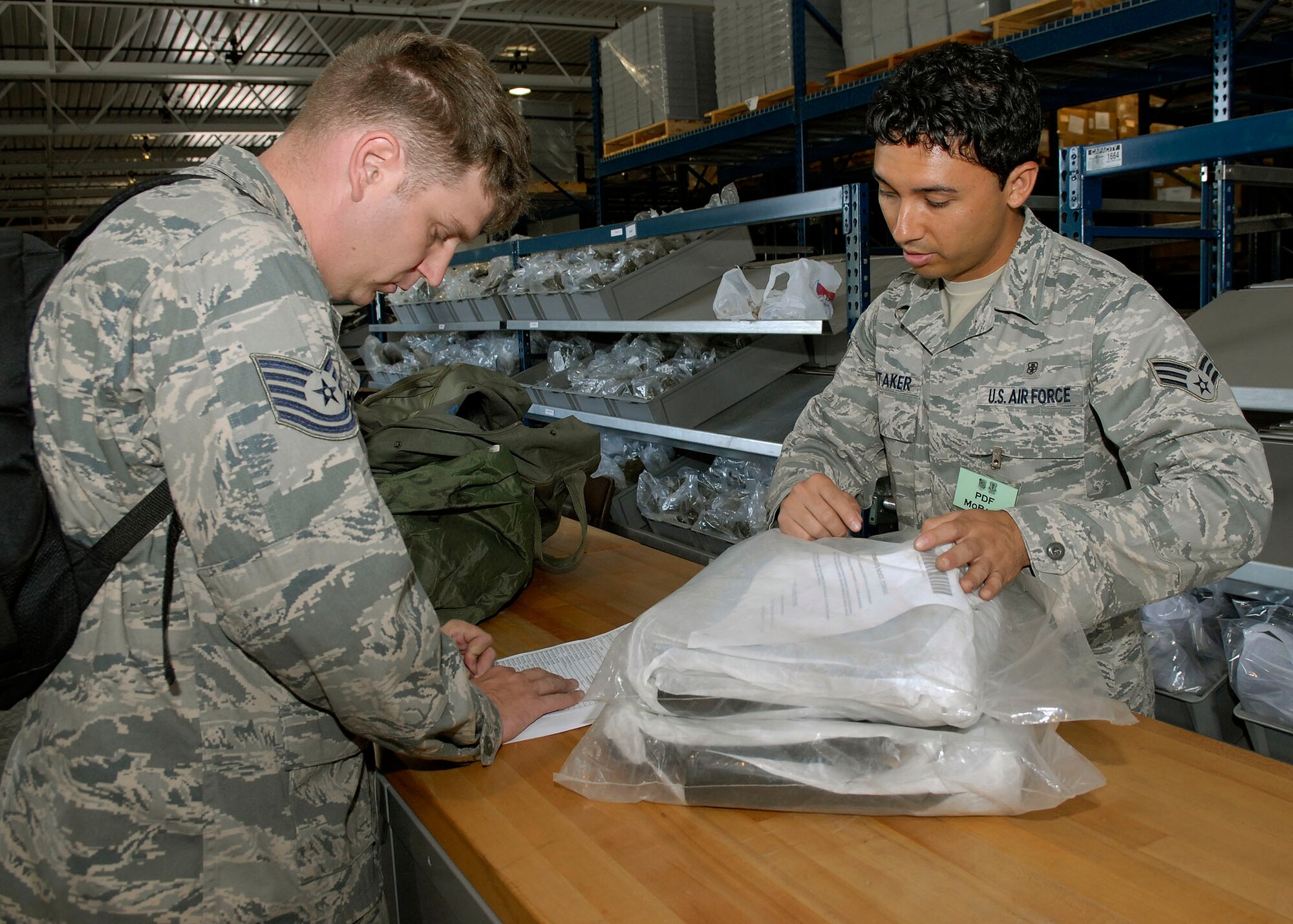 JOINT BASE PEARL HARBOR HICKAM, Hawaii--Senior Airman Sonny Whitaker, 15th Communication Squadron, verifies the serial number on a pair of chemical warfare boots, with 15th Aircraft Maintenance Squadron, during an Operational Readiness Exercise at the Personnel Deployment Function building here April 22. The PDF serves as the wing's last set of eyes ensuring all personnel are eligible for deployment. The ORE is designed to test 15th Air Wing's capabilities to respond to real world contingencies.  (U. S. Air Force photo/Tech. Sgt. Jerome S. Tayborn)
