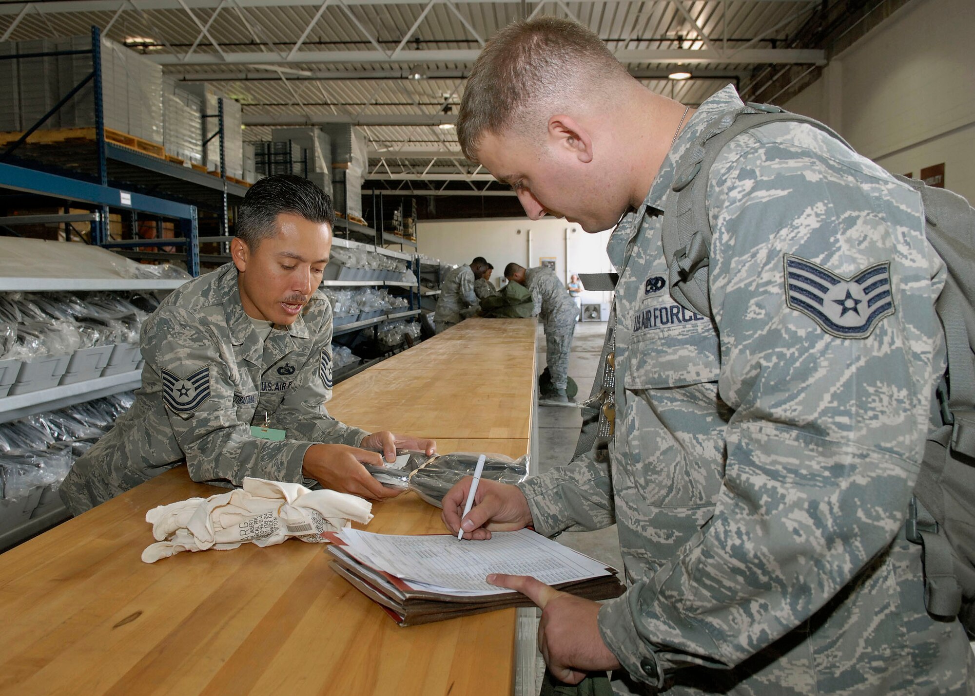 JOINT BASE PEARL HARBOR HICKAM, Hawaii--Tech. Sgt. Chris Chaikittirattana, 15th Communication Squadron, verifies a serial number on a pair of chemical warfare gloves, with Staff Sgt. Jason Chaltry, 15th Aircraft Maintenance Squadron, during an Operational Readiness Exercise at the Personnel Deployment Function building here April 22 here. The PDF serves as the 15th Airlift Wing's last set of eyes ensuring all personnel are eligible for deployment. The ORE is designed to test 15th AW capabilities to respond to real world contingencies.  (U. S. Air Force photo/Tech. Sgt. Jerome S. Tayborn)