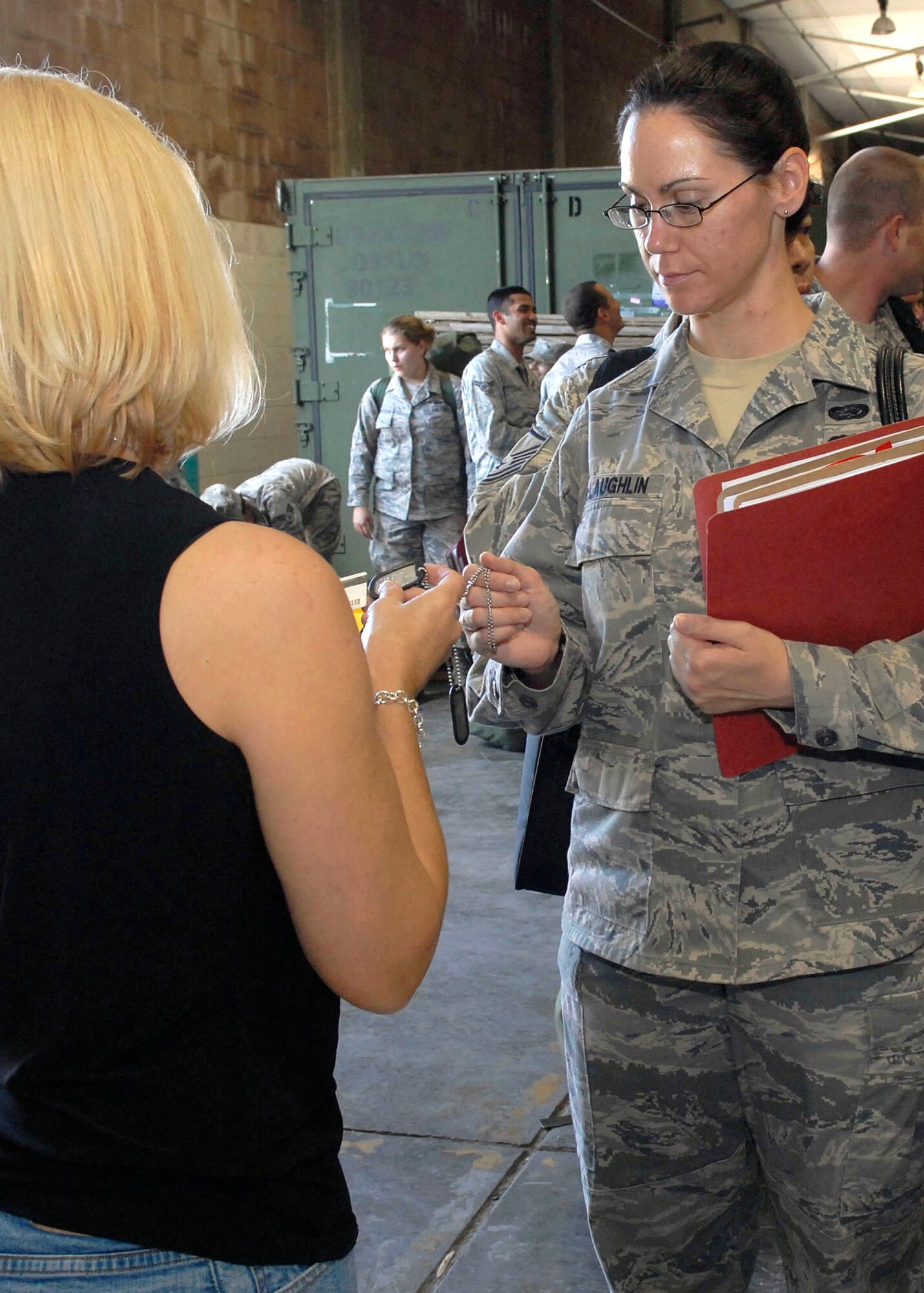 JOINT BASE PEARL HARBOR HICKAM, Hawaii--Cathy Loeschke, 15th Family Support Squadron , verifies the identity of  Technical  Sgt. Julie McLaughlin, 15th Aircraft Maintenance Squadron, by checking her military ID and dogs tags, during an Operational Readiness Exercise (ORE) at the Personnel Deployment Function (PDF) building at JBPHH, Hawaii, April 22, 2010. The PDF serves as the wing?s last set of eyes ensuring all personnel are eligible for deployment. The ORE is designed to test 15th Air Wing?s capabilities to respond to real world contingencies.  (U. S. Air Force photo/Tech. Sgt. Jerome S. Tayborn)