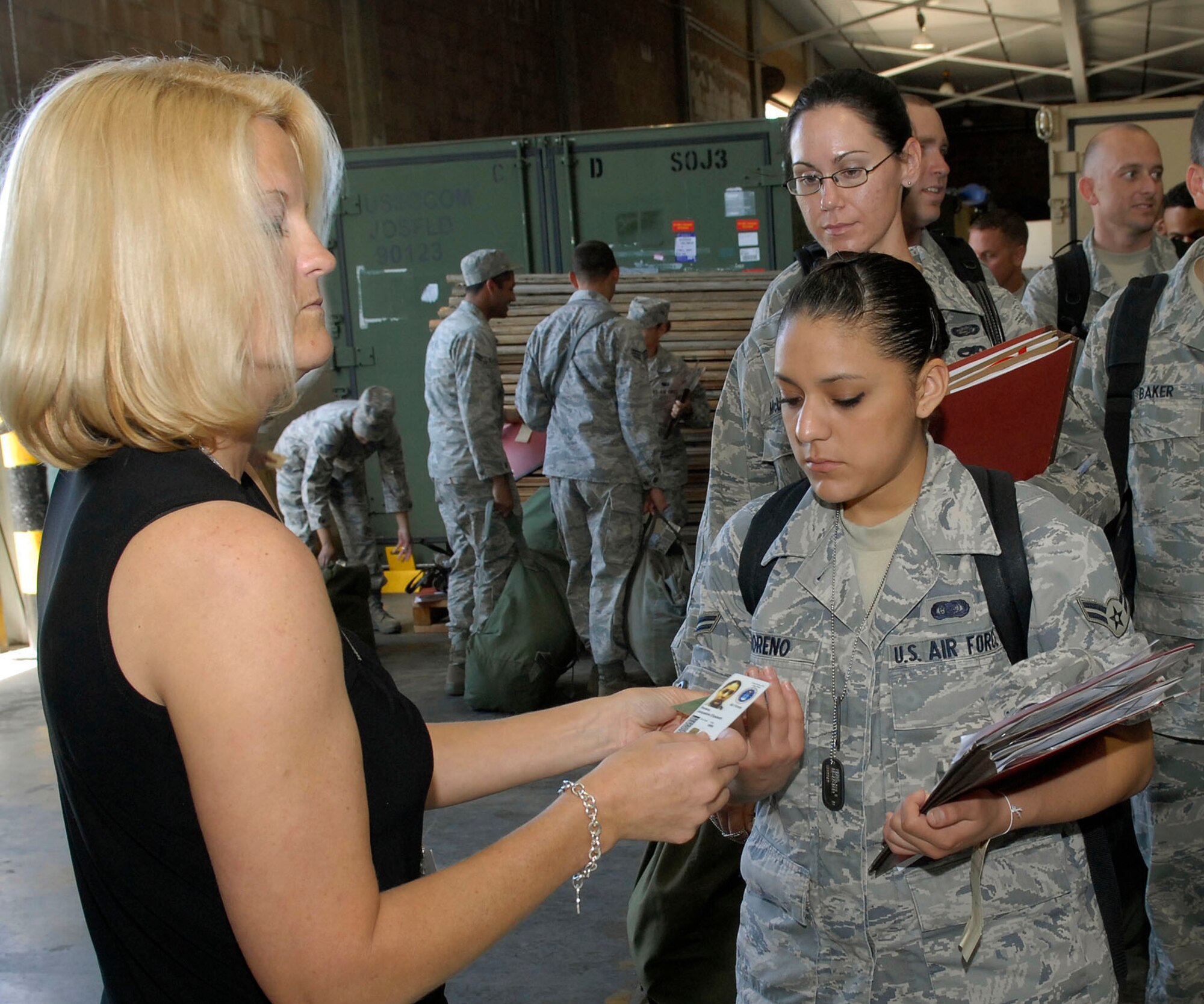 JOINT BASE PEARL HARBOR HICKAM, Hawaii--Cathy Loeschke, 15th Family Support Squadron, verifies the identity of  Airman First Class Jacqueline Moreno, 15th Aircraft Maintenance Squadron, by checking her military ID and dogs tags, during an Operational Readiness Exercise (ORE) at the Personnel Deployment Function (PDF) building at JBPHH, Hawaii, April 22, 2010. The PDF serves as the wing?s last set of eyes ensuring all personnel are eligible for deployment. The ORE is designed to test 15th Air Wing?s capabilities to respond to real world contingencies.  (U. S. Air Force photo/Tech. Sgt. Jerome S. Tayborn)
