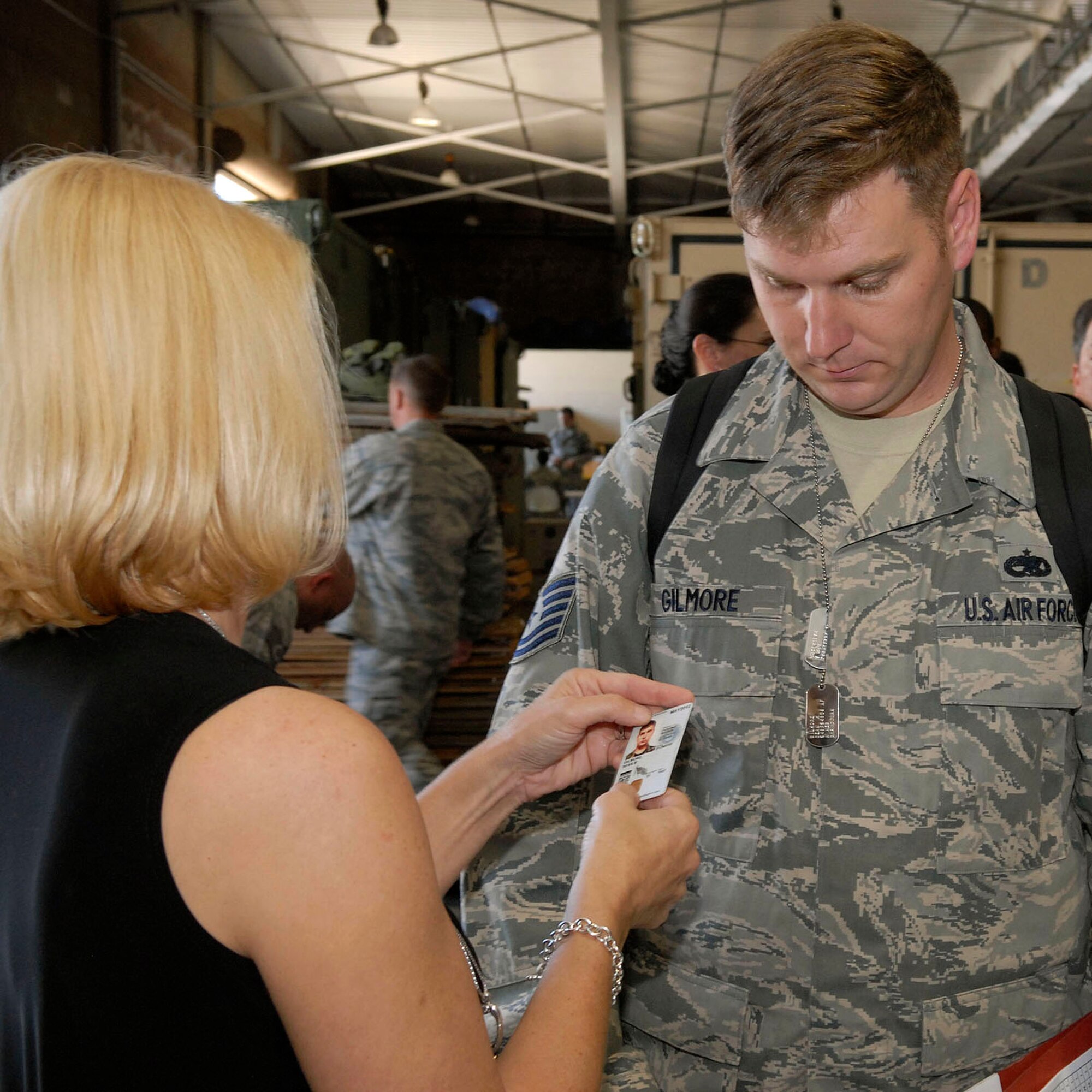 JOINT BASE PEARL HARBOR HICKAM, Hawaii--Cathy Loeschke, 15th Family Support Squadron, verifies the identity of  Technical Sgt. Shaun Gilmore, 15th Aircraft Maintenance Squadron, by checking his military ID and dogs tags, during an Operational Readiness Exercise (ORE) at the Personnel Deployment Function (PDF) building at JBPHH, Hawaii, April 22, 2010. The PDF serves as the wing?s last set of eyes ensuring all personnel are eligible for deployment. The ORE is designed to test 15th Air Wing?s capabilities to respond to real world contingencies.  (U. S. Air Force photo/Tech. Sgt. Jerome S. Tayborn)