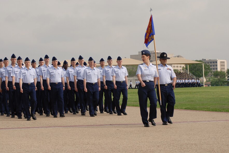 Lt. Col. Kelly Gwin, 433rd Airlift Wing commands basic trainees in formation while Staff Sgt. Thomas Perez, military training instructor, 326th Training Squadron, carries the squadron's guideon. The formation passes the reviewing stand during the 2010 Annual Basic Military Training Fiesta Parade, Lackland Air Force Base, Texas. (U.S. Air Force photo/Airman 1st Class Brian McGloin)
