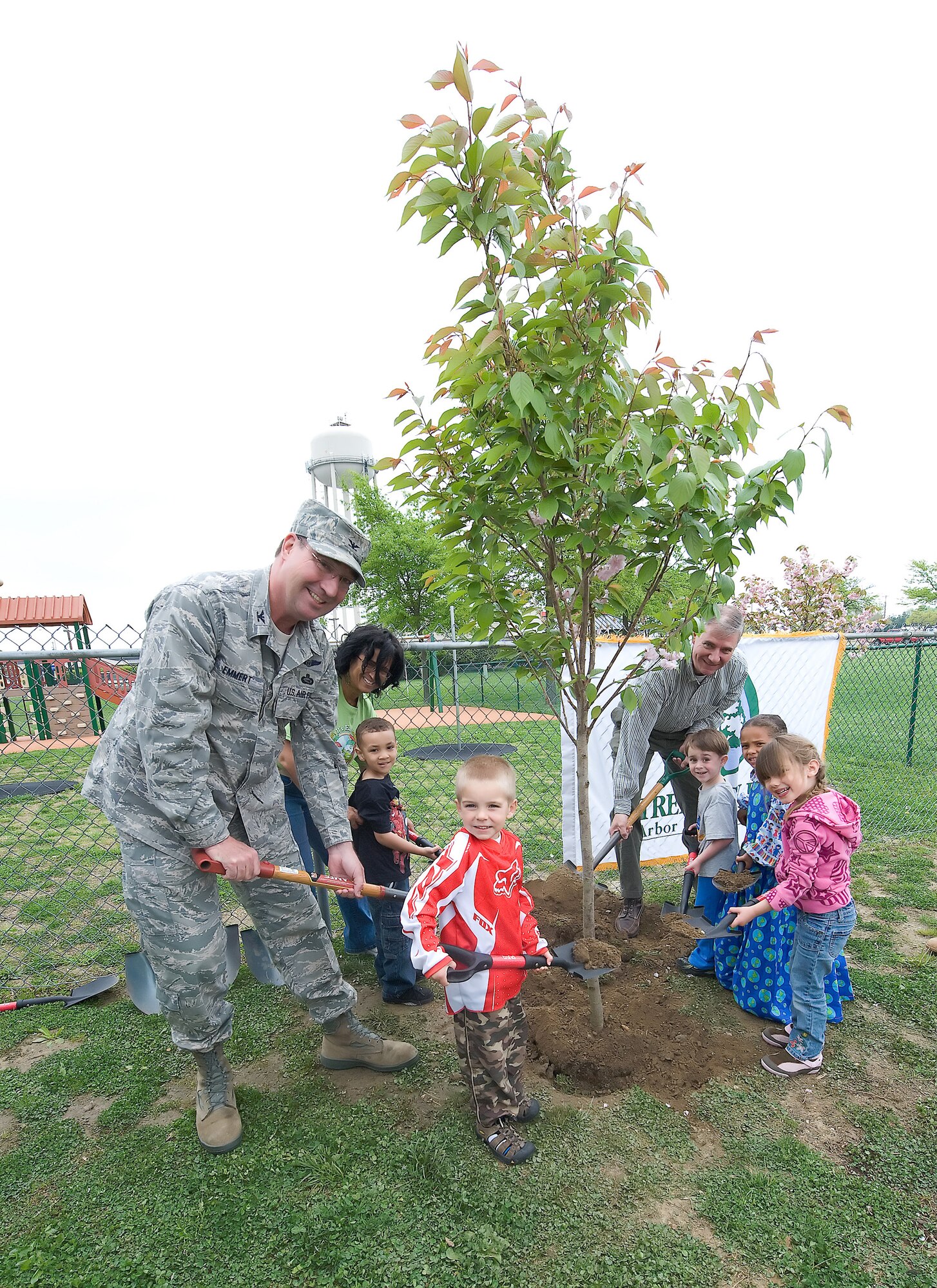 (Left) Col. Todd Emmert, 436th Maintenance Group commander, Child Development Center children and Michael Valenti, Delaware Forest Service acting state forester, work together to put the finishing touches on the tree planted for the 40th anniversary of Earth Day. The children used small spades to shovel in the dirt around the roots of the tree with the assistance of the two representatives. (U.S. Air Force photo/Brianne Zimny)