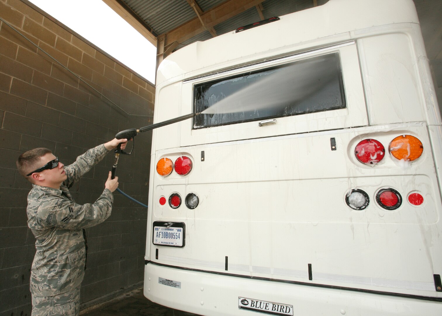 Airman 1st Class Adam Vargeson, 802nd Logistics Readiness Squadron, washes the back window of a bus at the Lackland vehicle maintenance yard April 20. The yard is equipped with a newly installed water recycling machine that will save one million gallons of water a year. (U.S. Air Force photo by Robbin Cresswell)