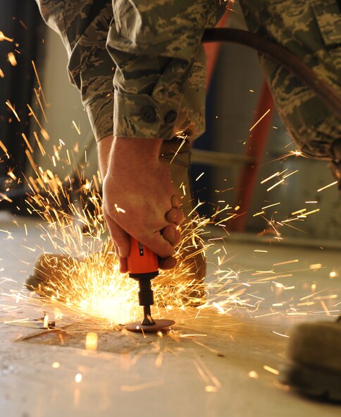 MOODY AIR FORCE BASE, Ga. -- Senior Airman Talmadge Borthwick, 23rd Equipment Maintenance Squadron aircraft maintenance journeyman, grinds away the metal anchors of an old machine to make way for a new power sheering machine here April 1. The new machine will allow for faster manufacturing of sheet metal used for aircraft maintenance. (U.S. Air Force photo by Airman 1st Class Benjamin Wiseman/RELEASED)