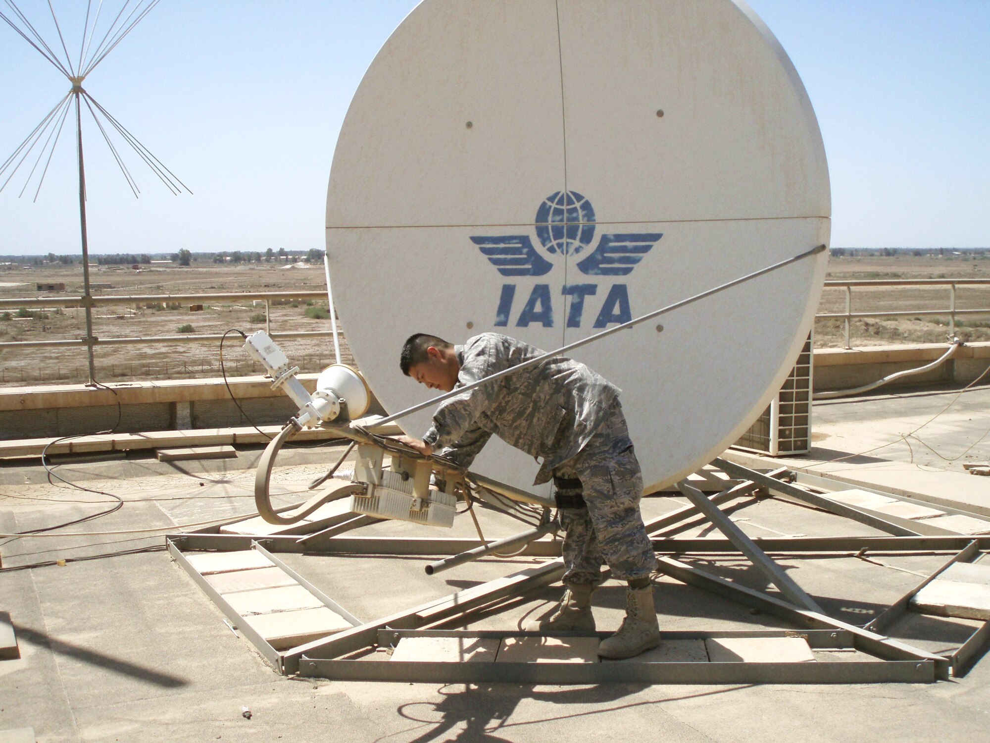 Capt. Kurando Mensen inspects a Very Small Aperture Terminal dish at a civilian airport March 17, 2010, in Iraq. Captain Mensen is a communications planner for the Air Component Coordination Element-Iraq. (Courtesy photo)   