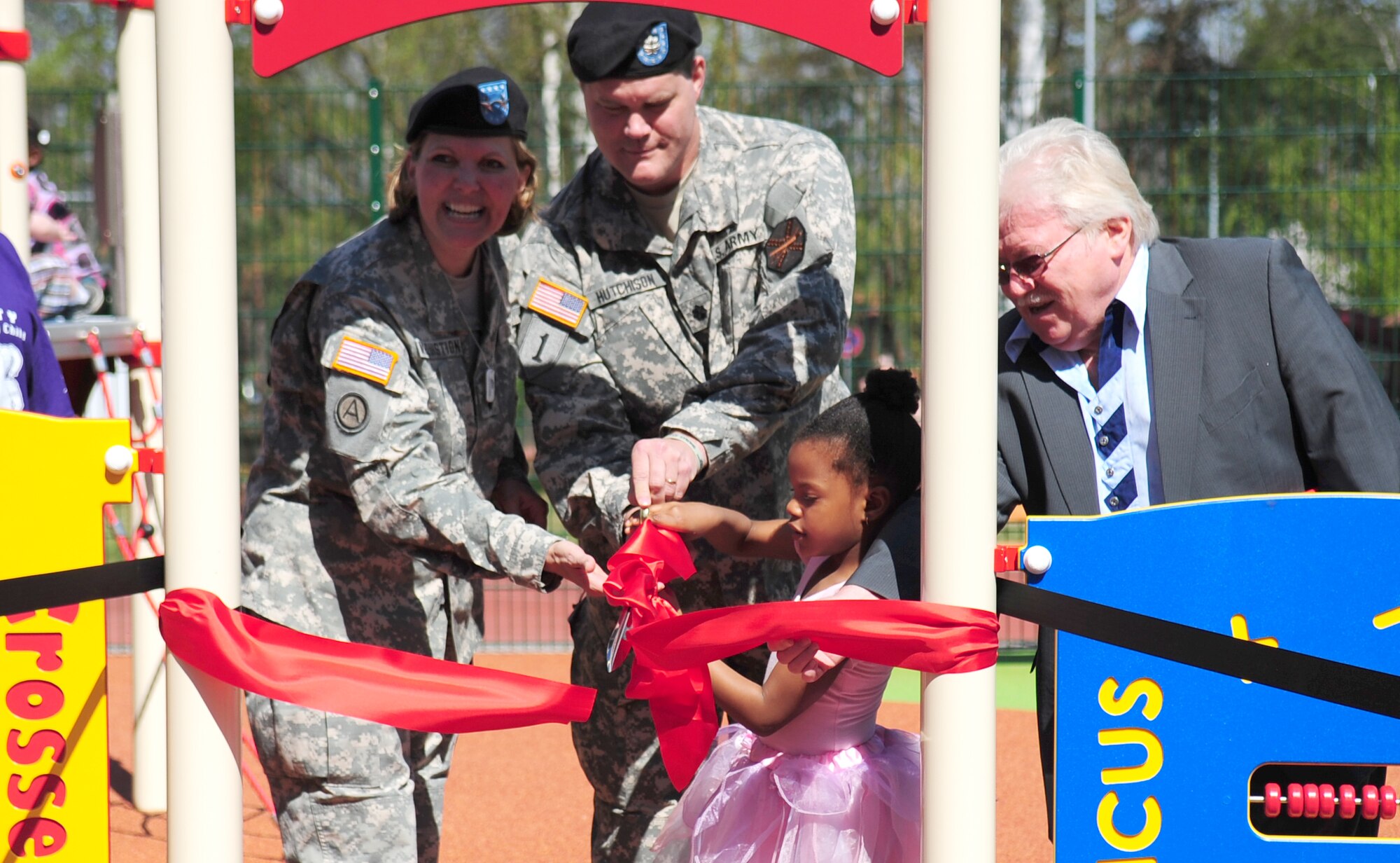 Naomi Belgrave, 5, daughter of U.S. Army Chief Warrant Officer Benito Belgrave, Charlie Company, Landstuhl Medical Evacuation Unit  UH-60 pilot, cuts the ribbon at the opening ceremony of Europe's first boundless playground with U.S. Army Major Gen. Patricia McQuinston, Commander of the 21st Theater Support Command, and Lt. Colonel Kevin S. Hutchinson, Commander of the U.S. Army Garrison Kaiserslautern.  The boundless playground is designed so that special needs family members are able to play side-by-side with other children.  (U.S. Air Force Photo by Staff Sgt. Jocelyn Rich)