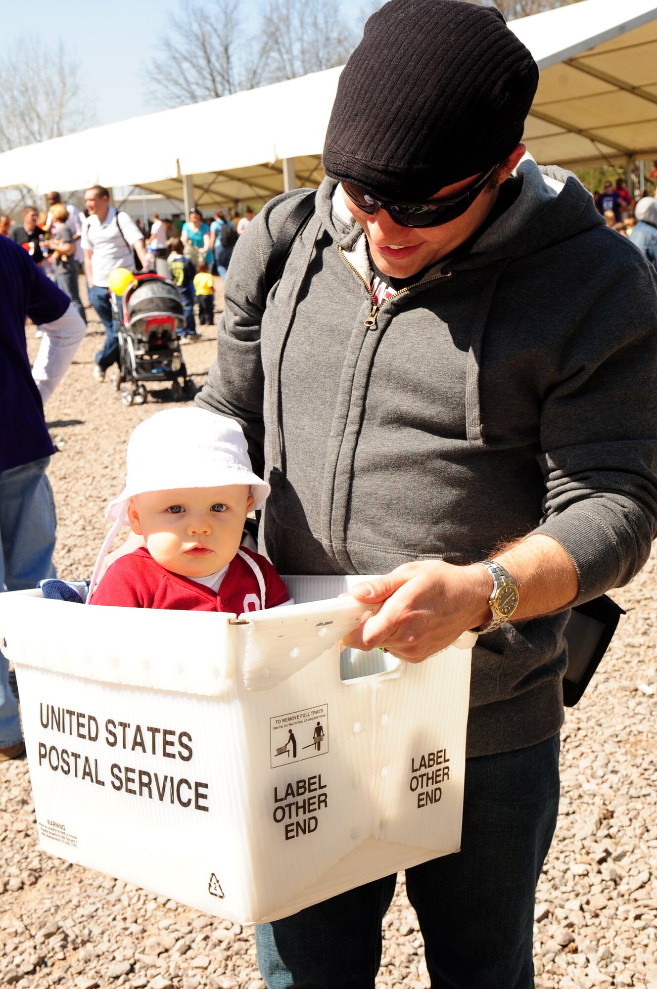 Nate Adams, University of Oklahoma employee, Ramstein Air Base education office, carries his special delivery, 10-month-old Glenn Adams, through the Kids Festival at Pulaski Barracks, Germany, April 24, 2010. The festival was held as a finale for Month of the Military Child.  Military members and NATO ID card holders were invited to come out and show their appreciation for the children.(U.S. Air Force photo by Staff Sgt. Jocelyn Rich)