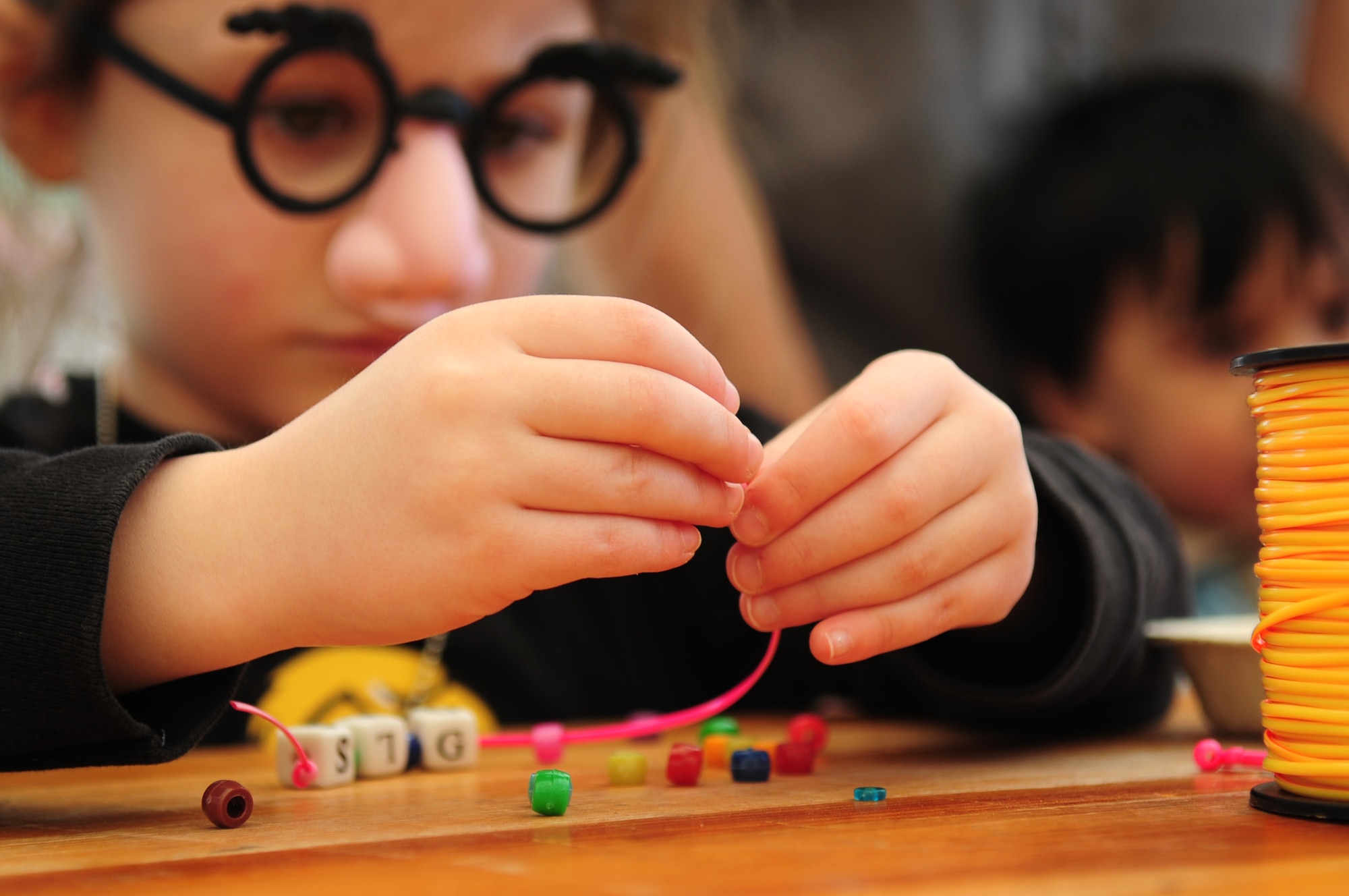 Gracie Solomon, daughter of U.S. Air Force Tech. Sgt. Christopher Solomon , 86th Operation Support Squadron, makes a bracelet out of beads at a craft table at the Kids Festival on Pulaski Barracks, Germany, April 24, 2010.  The festival was held as a finale for Month of the Military Child.  Military members and NATO ID card holders were invited to come out and show their appreciation for the children.(U.S. Air Force photo by Staff Sgt. Jocelyn Rich)