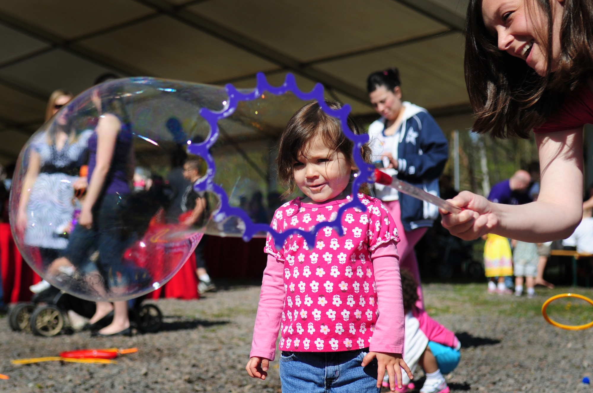 Patty Medina, wife of Tech. Sgt. Eduardo Media, 721st Aircraft Maintenance crew chief, plays with a giant bubble maker with her daughter Olivia, 2, during the Kids Festival at Pulaski Barracks, April 24, 2010. The festival was held as a finale for Month of the Military Child.  Military members and NATO ID card holders were invited to come out and show their appreciation for the children.(U.S. Air Force photo by Staff Sgt. Jocelyn Rich)
