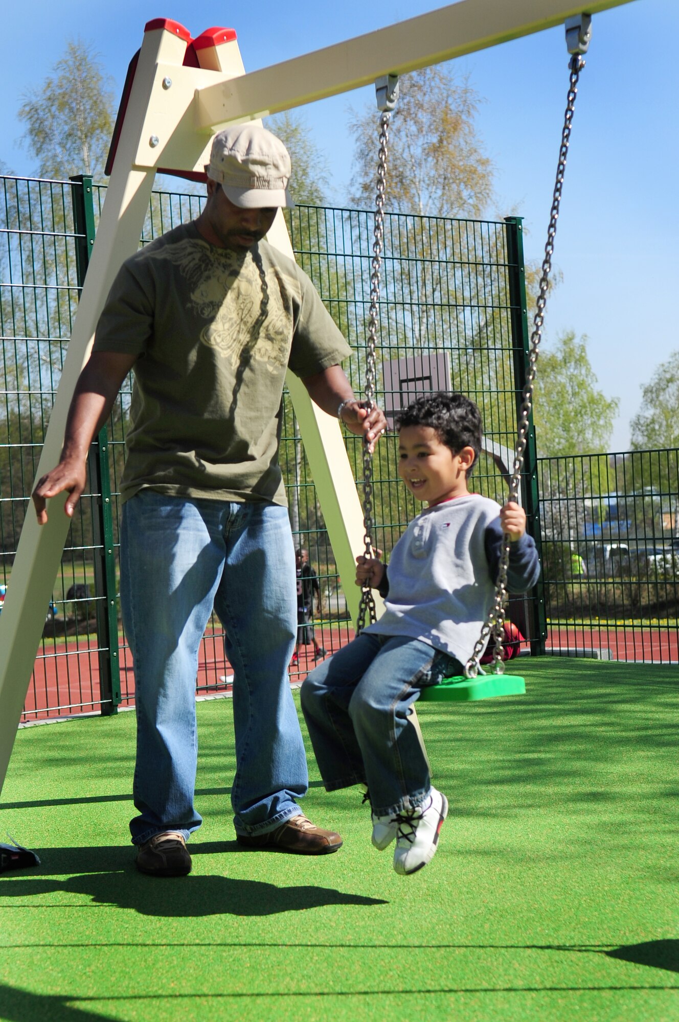 U.S. Air Force Tech. Sgt. Tremayne Neals, 86th Air Evacuation Squadron, Air Medical Evacuation Technician, guides his son Isiah, 3, on the swings at the newly opened boundless playground, during the Kids Festival, Pulaski Barracks, Germany, April 24, 2010. The festival was held as a finale for Month of the Military Child.  Military members and NATO ID card holders were invited to come out and show their appreciation for the children.(U.S. Air Force photo by Staff Sgt. Jocelyn Rich)