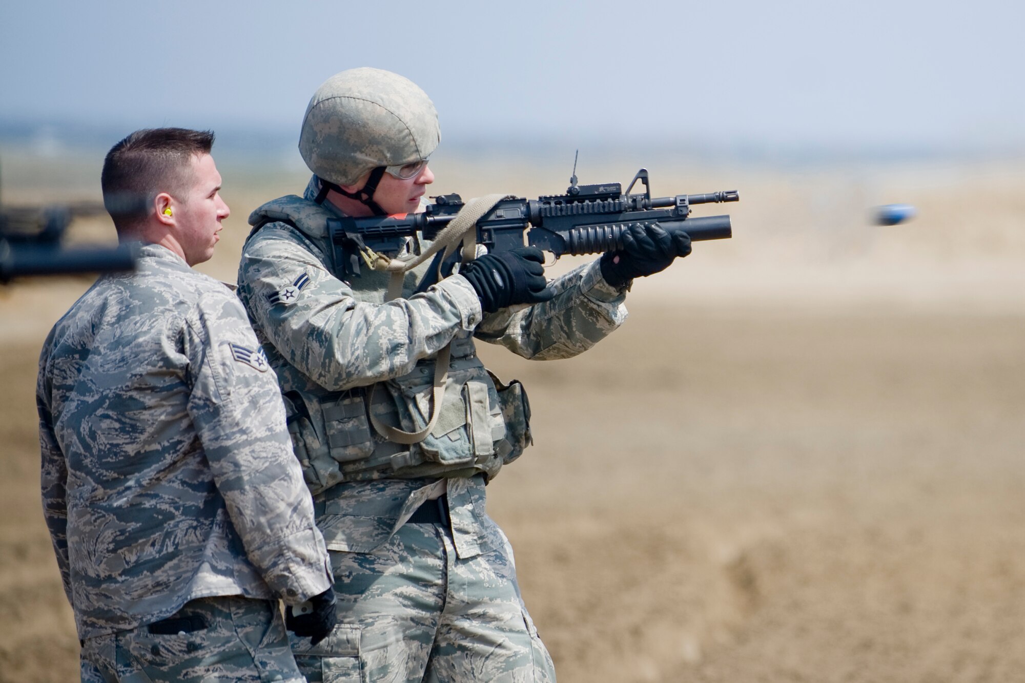MISAWA AIR BASE, Japan -- Airman 1st Class Daniel Emery, 35th Security Forces Squadron patrolman, fires an M203 grenade launcher with guidance from Senior Airman Jordan Fisher, 35th SFS combat-arms instructor, during training April 27 at Draughon Range. During the training, students fired M781 practice rounds which are used for qualifying on the M203. The tip of the round is filled with orange chalk that creates a cloud on impact, allowing the instructor to see where the round hit. (U.S. Air Force photo/Senior Airman Jamal D. Sutter)