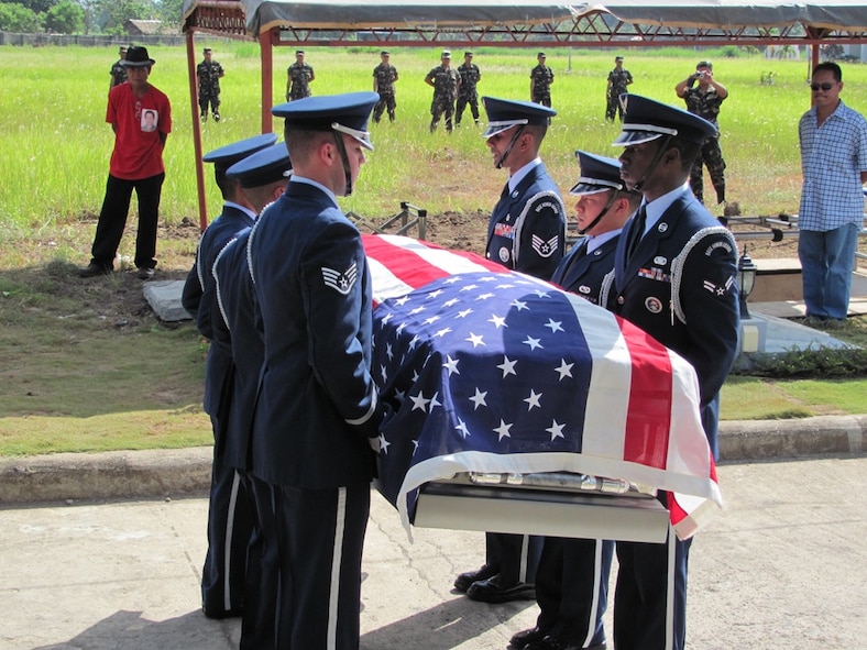 Members of the Kadena Air Base Honor Guard hold the flag-draped casket of Tech. Sgt. Raymond Natividad during a funeral detail. In the background, the firing team from the Philippine army prepares to render the 21-gun salute, finishing out the full honors ceremony April 27, 2010. (U.S. Air Force photo/Tech. Sgt. Brian Roberts) 