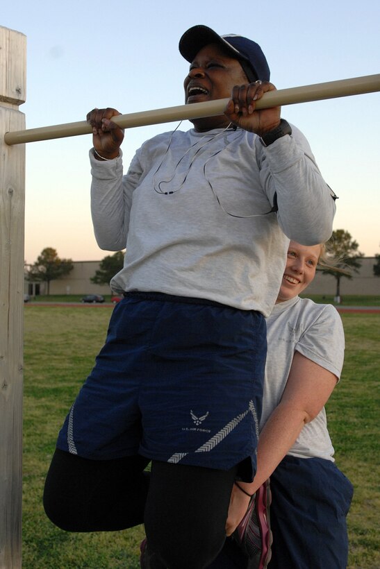 LANGLEY AIR FORCE BASE, Va. - Master Sgt. Harriet Early, Air Combat Command Training Support Squadron program manager practices pull-ups with the help of Airman 1st Class Sashia Pendleton, 633d Force Support Squadron food services journeyman during the “Back to Basics” class April 19. The eight-week course is designed to help Airmen improve their physical training performance through a rigorous daily workout program. (U.S. Air Force photo/Airman 1st Class Gul Crockett) 
