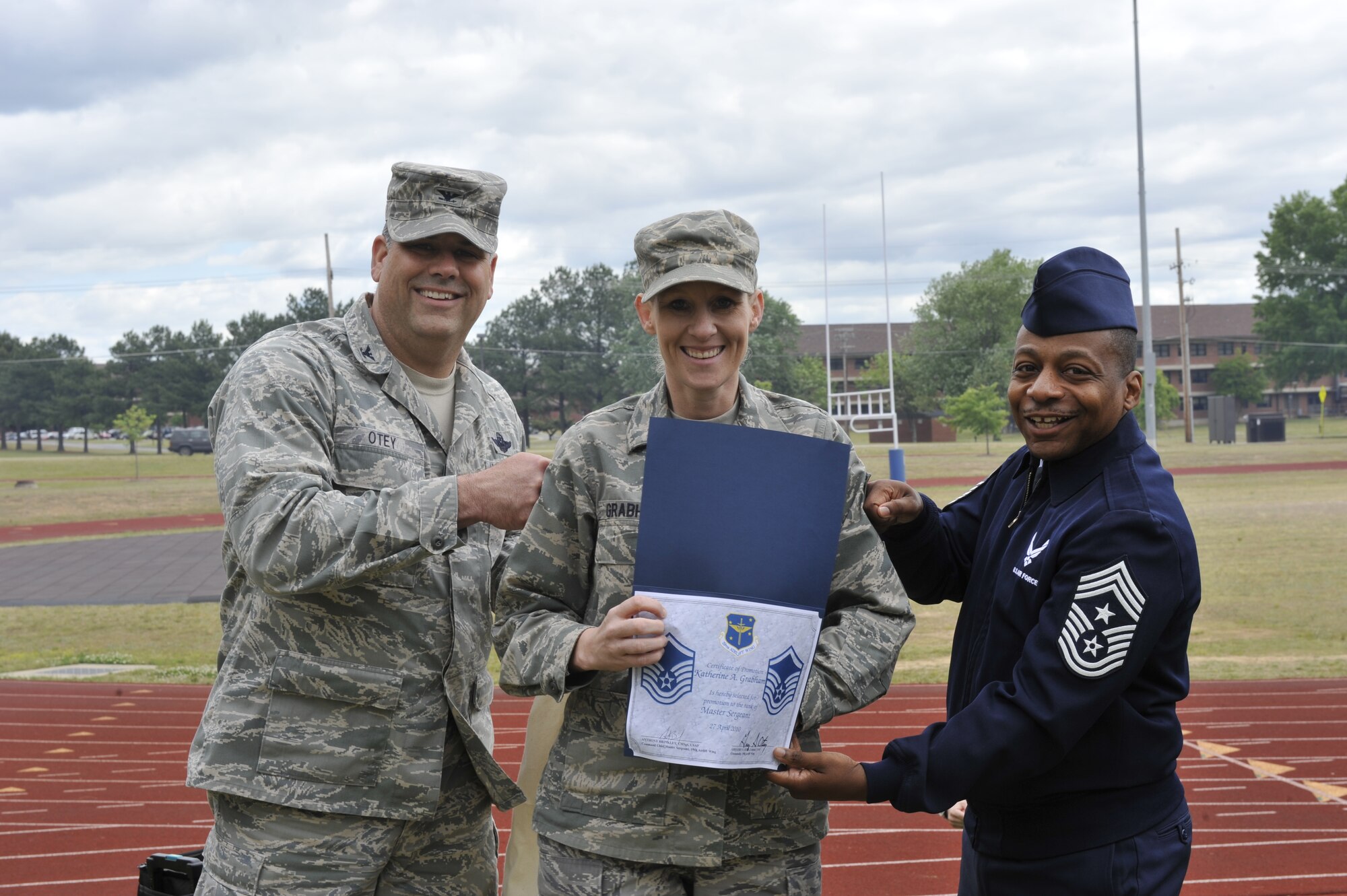 (Left) Col. Greg Otey, 19th Airlift Wing commander; and (right) Chief Master Sgt. Anthony Brinkley, 19th AW command chief; congratulate Master Sgt. Kati Grabham, 19th AW Public Affairs, April 27 following her Stripes for Exceptional Performers promotion during the commander's call at Warfit Track. The all call was held to recognize Unit Compliance Inspection exceptional performers. (U.S. Air Force photo by Senior Airman Christine Clark)