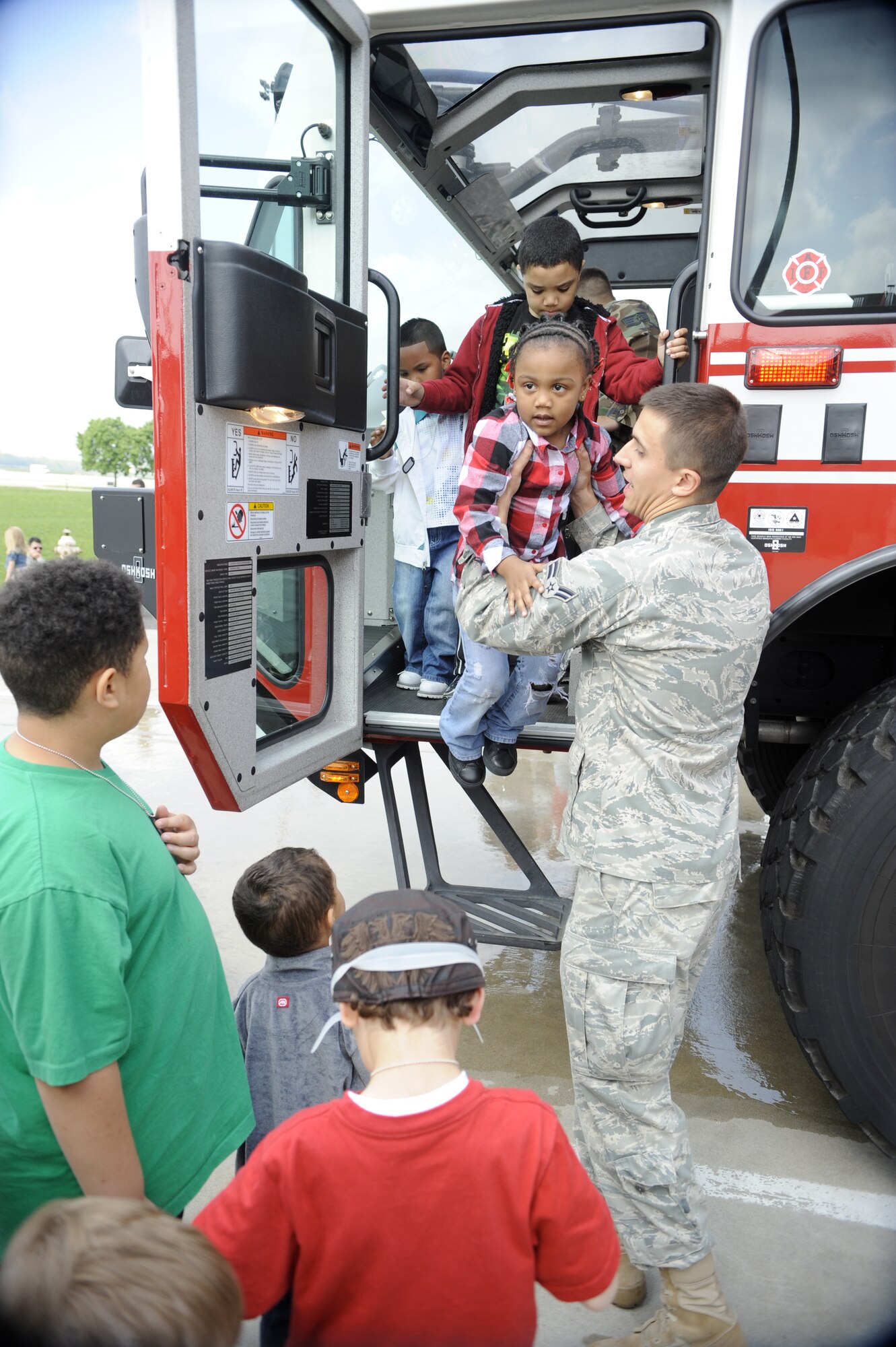 Airman 1st Class Milan Tomic, a 87th Civil Engineer Squadron fire fighter, helps children get in and out of a fire truck during a tour on Bring Your Child to Work Day.  The 514th Air Mobility Wing hosted the event  April 22. (U.S. Air Force photo/Carlos Cintron)