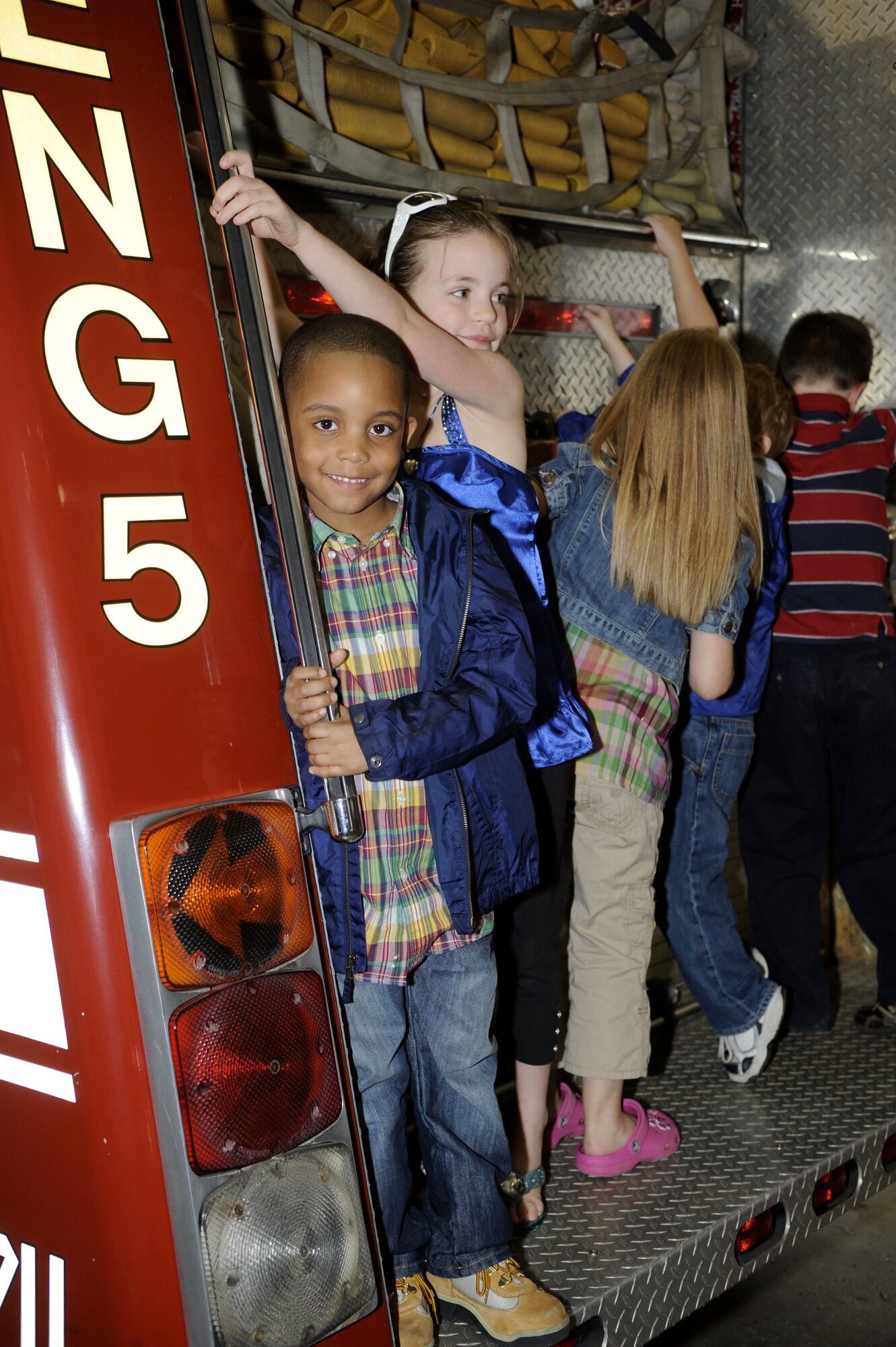 Zyhmir Tucker, 5, son of Cheryl Robinson, and Sydney Schier, 8, daughter of Maj. Ron Schier ,732nd Airlift Squadron pilot, climb onto the back of a fire engine duing a tour of the fire department April 22. A tour of the fire station was one of several events comprising the 514th Air Mobility Wing's Bring Your Child to Work Day. (U.S. Air Force photo/Carlos Cintron)