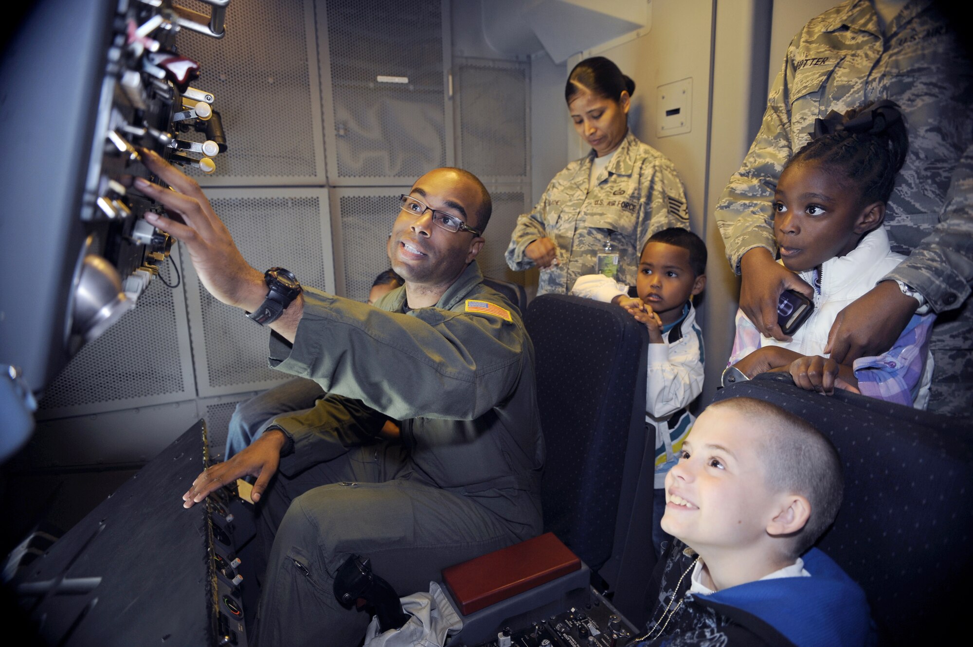Staff Sgt. Jett Klexton, 2nd Air Refueling Squadron boom operator, shows a group of children how the instrument panels work during mid-air refueling operations. Staff Sgt. Ibetly Alache, 514th Force Support Squadron and son Uziel watch along with Khamari Trotter, daughter of Tech. Sgt. Faunicia Trotter, 21st Air Mobility Operations Squadron, Tech Sgt. Tyrone Trotter, 305th Maintenance Squadron, and Robert  McDonough, brother of Senior Airman Allisha Wennersten, 305th Operations Group. (U.S. Air Force photo/Carlos Cintron)