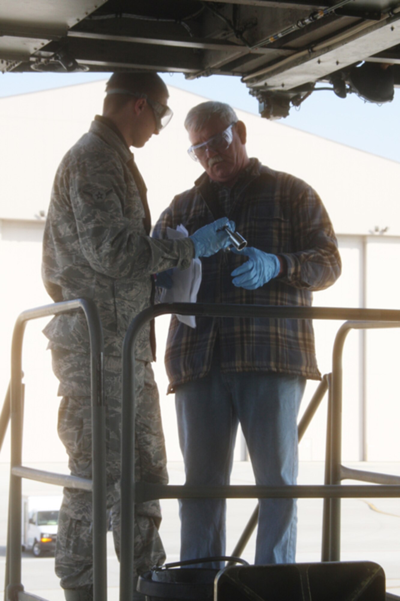 WRIGHT-PATTERSON AIR FORCE BASE, Ohio -- Harold Miller, an Air Force civilian hired temporarily to help complete contingency ISO inspections here, mentors Airman Keith Patton, who recently finished technical school, as they complete repairs on the forward loading systems.  Both men are part of the 445th Aircraft Maintenance Squadron.  (U.S. Air Force Photo/Staff Sgt. Amanda Duncan)