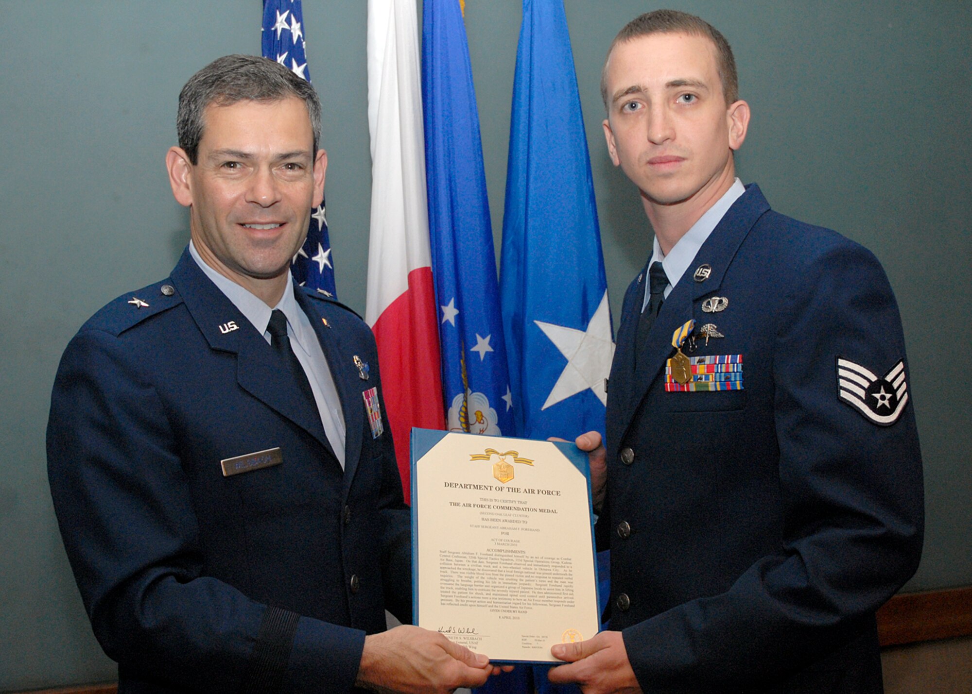 Staff Sgt. Aaron Sanders stands next to Brig. Gen. Ken Wilsbach, 18th Wing commander, after receiving the Air Force Commendation Medal for an act of courage April 26. Sergeant Sanders and Staff Sgt. Abraham Forehand, from the 353rd Special Operations Group, both received medals for pulling a man pinned under an automobile after an off-base accident March 3. (U.S. Air Force photo / Airman 1st Class Jarvie Wallace)
