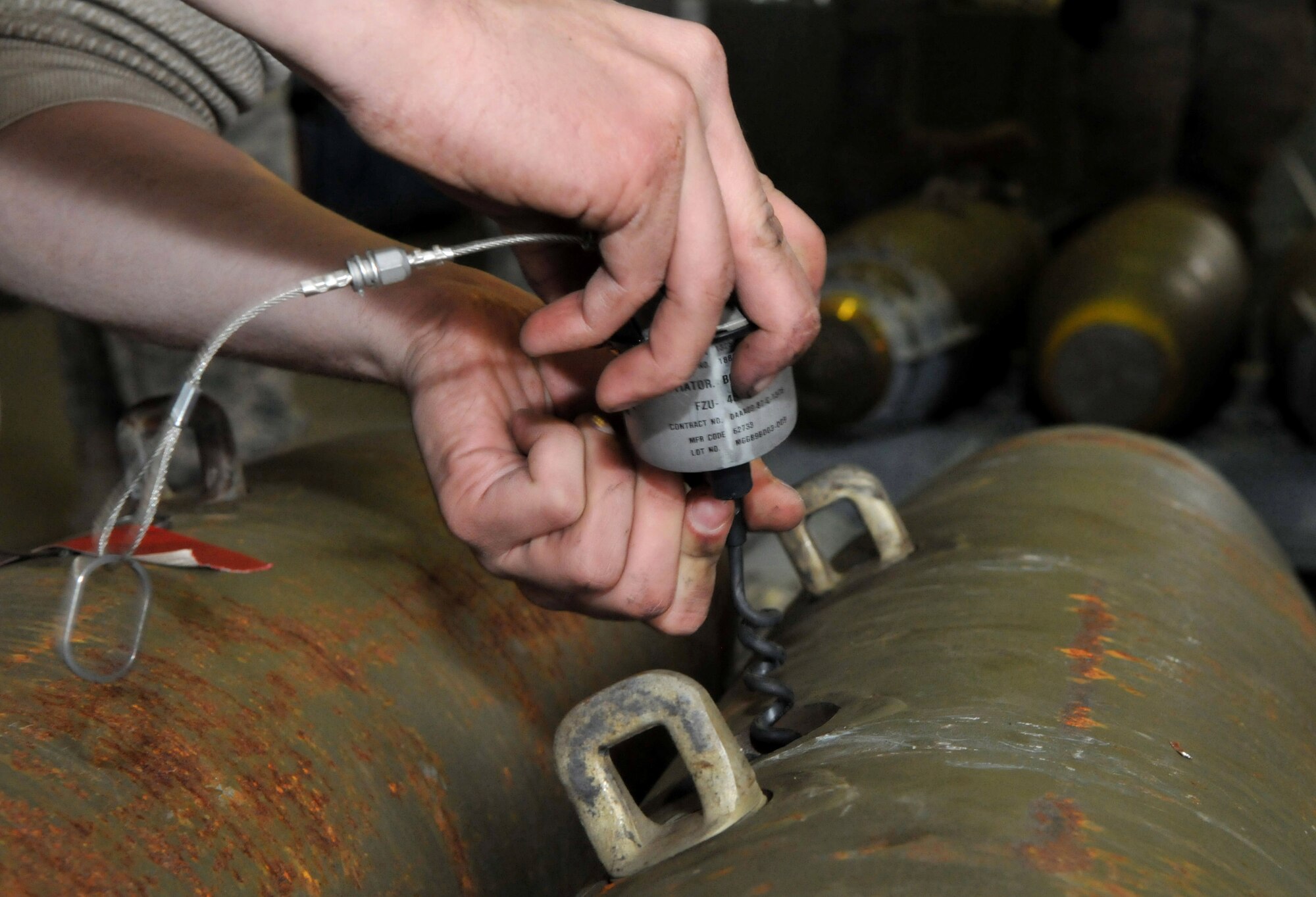 A conventional maintenance crew member with the 8th Maintenance Squadron, Kunsan Air Base, Republic of Korea, connects a fuse cable to an initiator on a live Joint Direct Attack Munition GBU-38 during Red Flag-Alaska at Eielson Air Force Base, Alaska, April 16. This connection arms the fuse, allowing the bomb to explode upon impact. (U.S. Air Force photo/Capt. Shannon Collins)