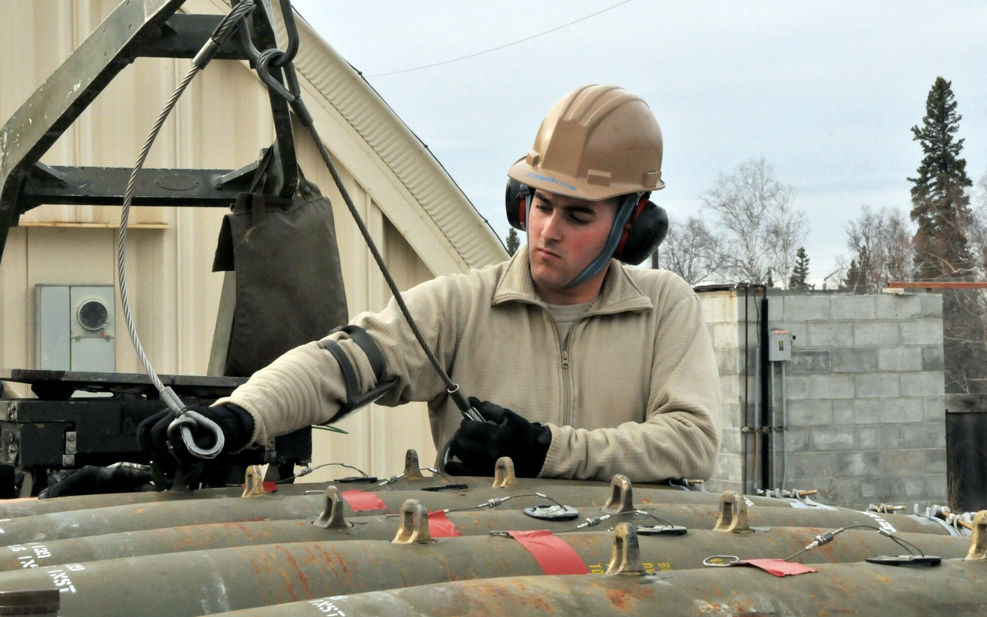 Senior Airman Jake Thibodeau, a conventional maintenance crewmember, unhooks slings from a jammer and a Joint Direct Attack Munition GBU-38 before securing it onto a munitions trailer during Red Flag-Alaska at Eielson Air Force Base, Alaska, April 16. Airman Thibodeau is deployed from the 8th Maintenance Squadron, Kunsan Air Base, Republic of Korea. (U.S. Air Force photo/Capt. Shannon Collins)