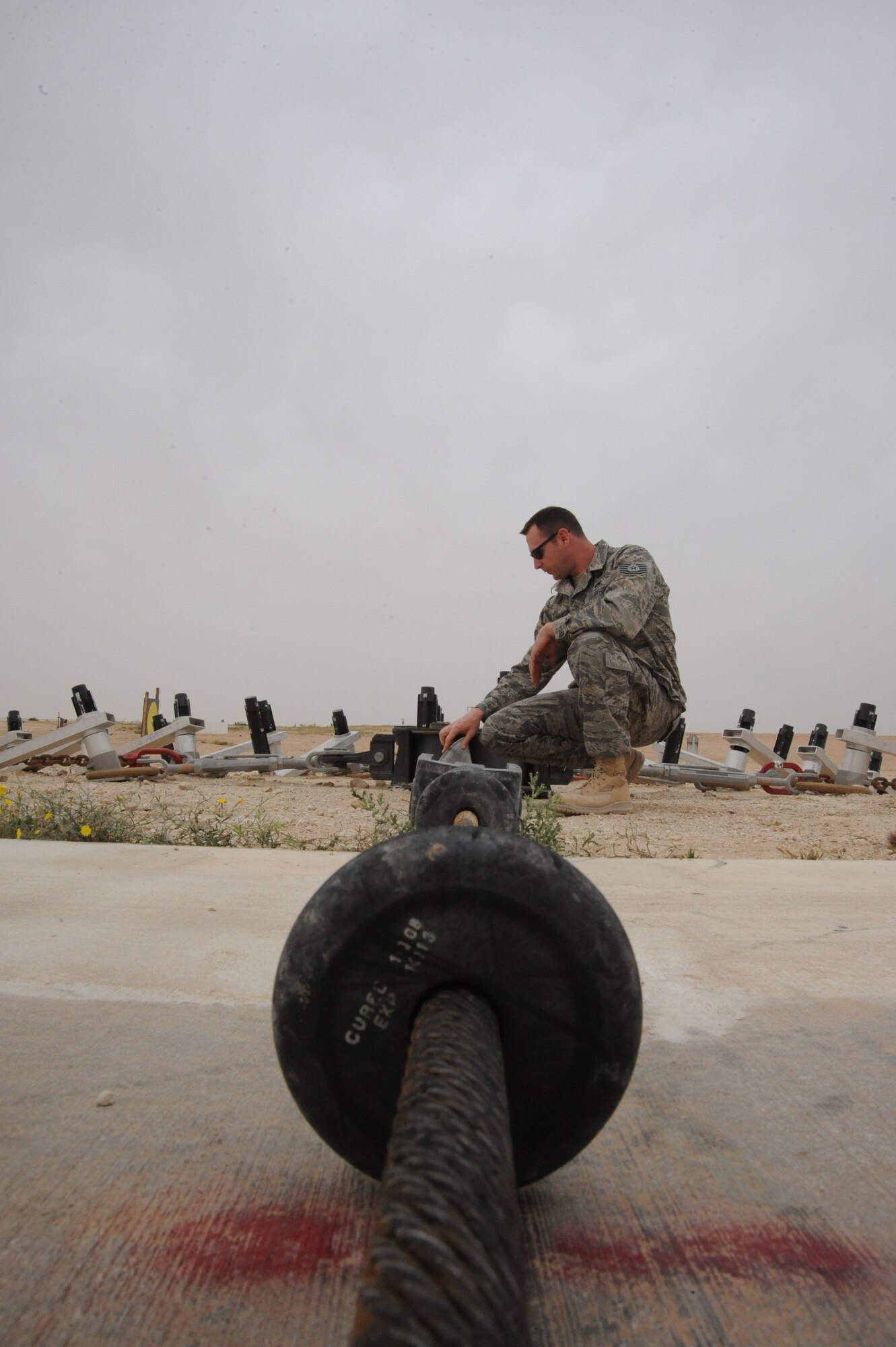 Air Force Tech. Sgt. Jeremey McLeod , barrier maintenance NCOIC, 532nd Expeditionary Operations Support Squadron, inspects an arresting cable, Al Asad, Iraq, April 17, 2010. Especially in a desert environment, it’s important to do weekly, monthly, and quarterly inspections to ensure equipment is working properly at all times. (U.S. Air Force photo/Master Sgt. Trish Bunting/Released)