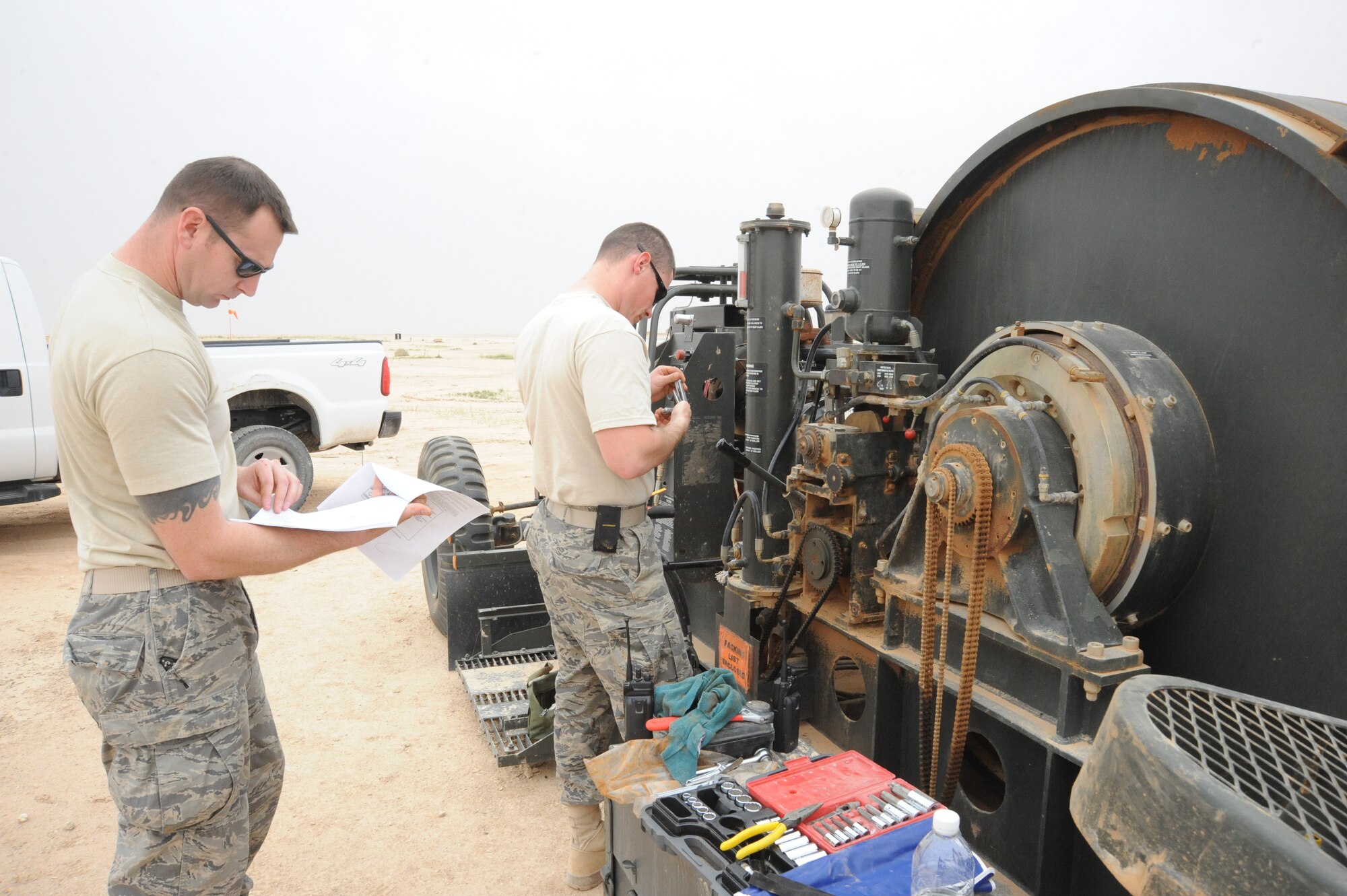 Air Force Tech. Sgt. Jeremey McLeod (left), barrier maintenance NCOIC,  and Airman 1st Class Anton Nashchechich, barrier maintenance technician, both from the 532nd Expeditionary Operations Support Squadron, perform their quarterly checks on the mobile aircraft arresting system barrier arresting kit-12, Al Asad, Iraq, April 17, 2010. Especially in a desert environment, it’s important to do weekly, monthly, and quarterly inspections to ensure the equipment is working properly at all times. (U.S. Air Force photo/Master Sgt. Trish Bunting/Released)
