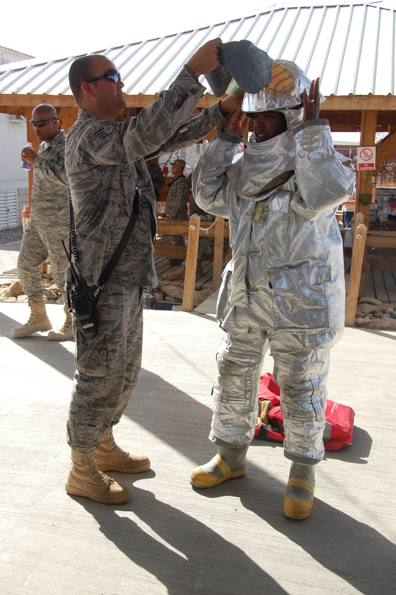 U.S. Air Force Staff Sgt. Matthew Dodge, 386th Expeditionary Civil Engineer Squadron firefighter, helps Senior Master Sgt. Nicole Jackson of the 386th Force Support Squadron try on a fire suit April 24, 2010 during the 386th ECES open house at an air base in Southwest Asia. Dozens of Airmen participated in the event in which they got an upclose look at fire department, explosive ordnance disposal and emergency management response equipment and spoke with experts in each career field. (U.S. Air Force photo by Tech. Sgt. Lindsey Maurice/Released)