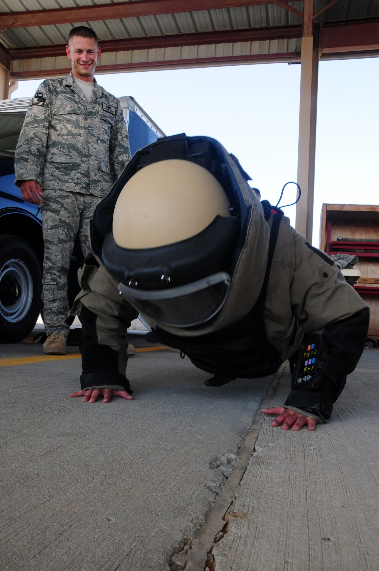 U.S. Air Force Staff Sgt. Dennis Barnhart of the 386th Expeditionary Civil Engineer Squadron Explosive Ordnance Disposal flight watches as Senior Airman Leanne Hardin of the 386th Expeditionary Logistics Readiness Squadron does pushups dressed in a bomb suit April 24, 2010 during the 386th ECES open house at an air base in Southwest Asia. Dozens of Airmen participated in the event in which they got an upclose look at fire department, explosive ordnance disposal and emergency management response equipment and spoke with experts in each career field. (U.S. Air Force photo by Staff Sgt. Lakisha A. Croley/Released)