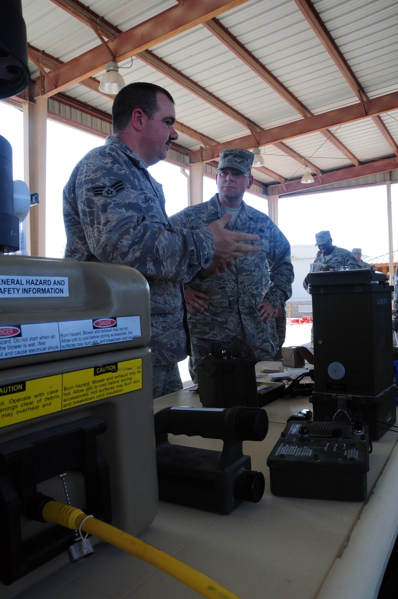 U.S. Air Force Senior Airman Wade Baker of the 386th Expeditionary Civil Engineer Squadron Emergency Management flight discuses the intricacies of the emergency management program with Master Sgt. Daniel Greene of the 386th Expeditionary Logistics Readiness Squadron Fuels Management flight April 24, 2010 during the 386th ECES open house at an air base in Southwest Asia. Dozens of Airmen participated in the event in which they got an upclose look at fire department, explosive ordnance disposal and emergency management response equipment and spoke with experts in each career field. (U.S. Air Force photo by Staff Sgt. Lakisha A. Croley/Released)  